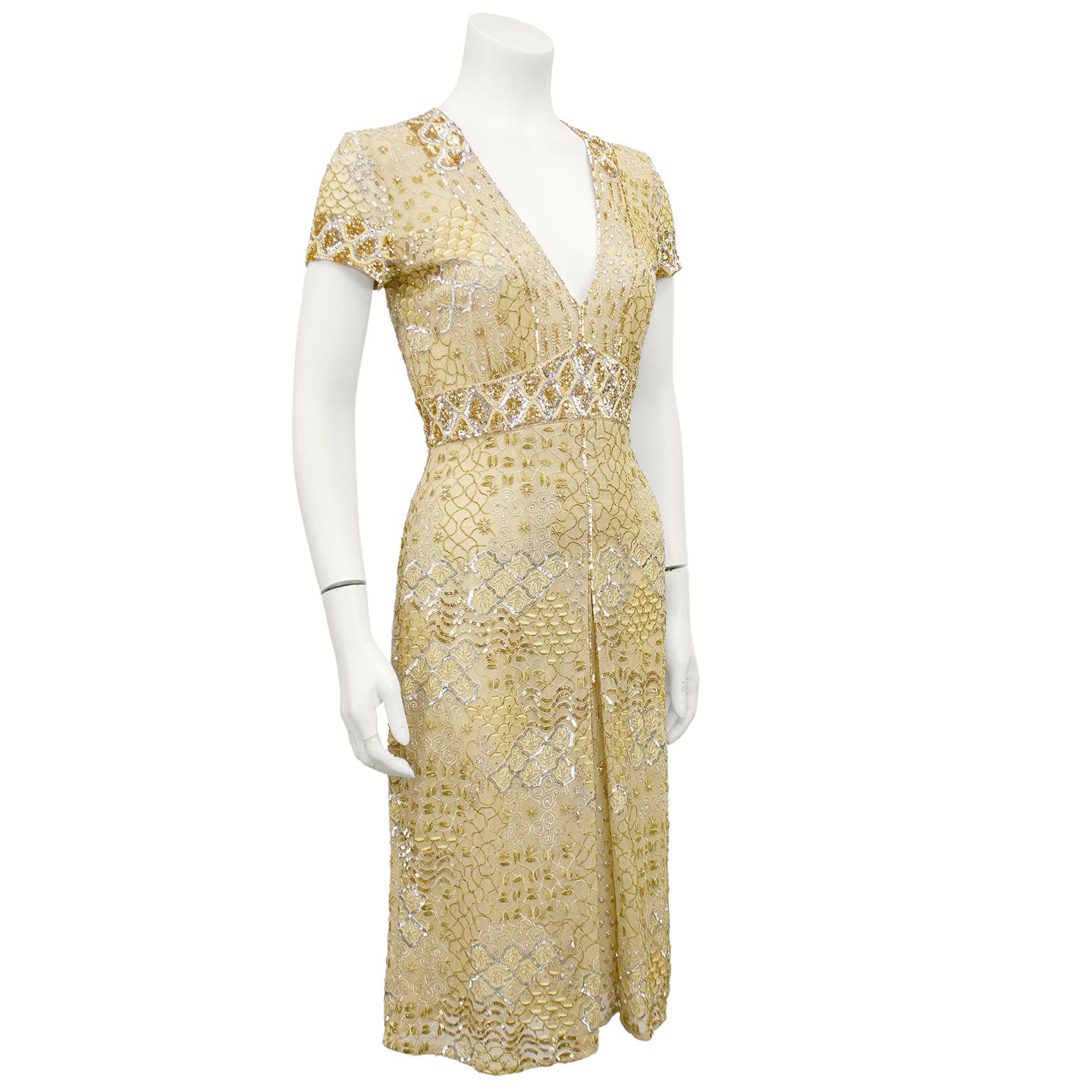 Glamorous 2000s Naeem Khan cocktail dress. Gold with all over gold and silver sequins, hand beading and tambour stitching. Short sleeve with a v neck line. Skirt features an inverted pleat, adding shape and movement. A classic shape with beautiful