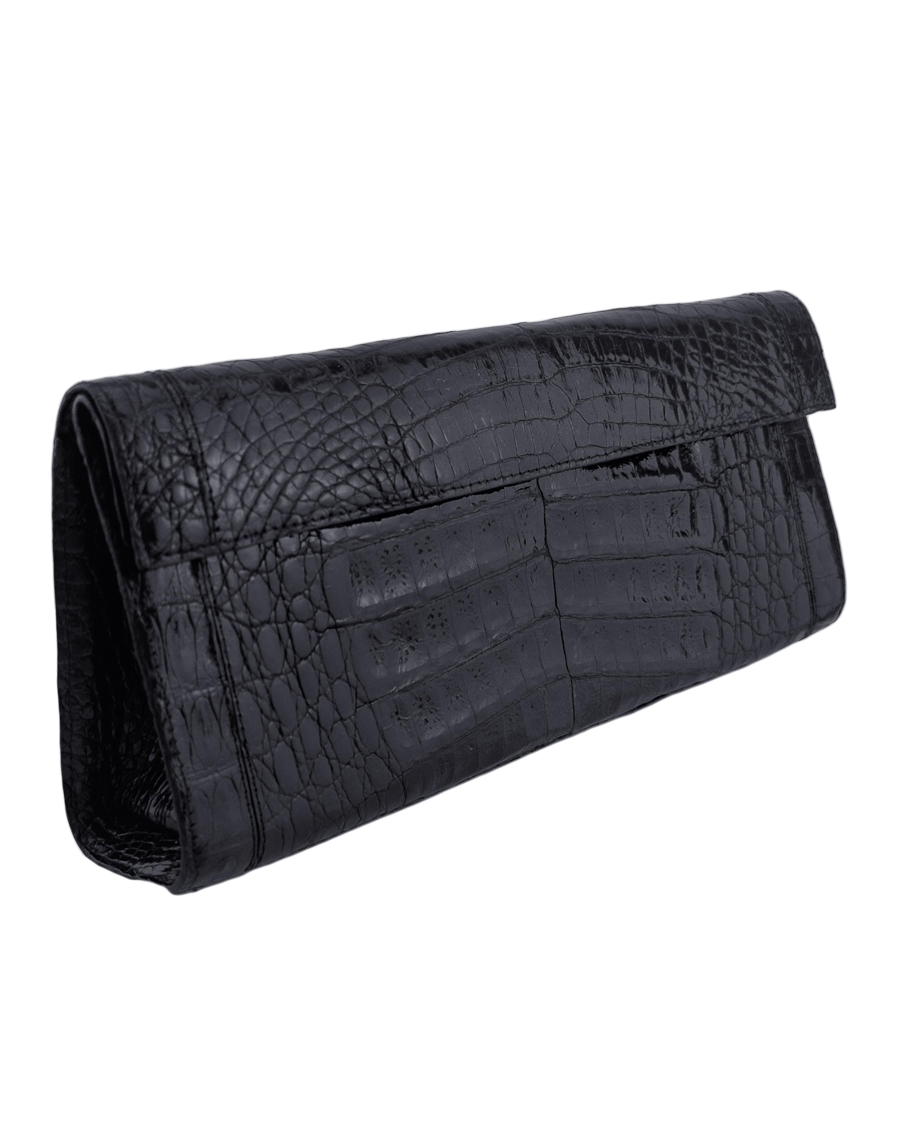 Chic, sleek and simple black crocodile evening clutch from the late 2010s. Narrow rectangular and envelope shape with a fold over flap closure that fastens magnetically. Chocolate brown suede interior with one large compartment and two open slit