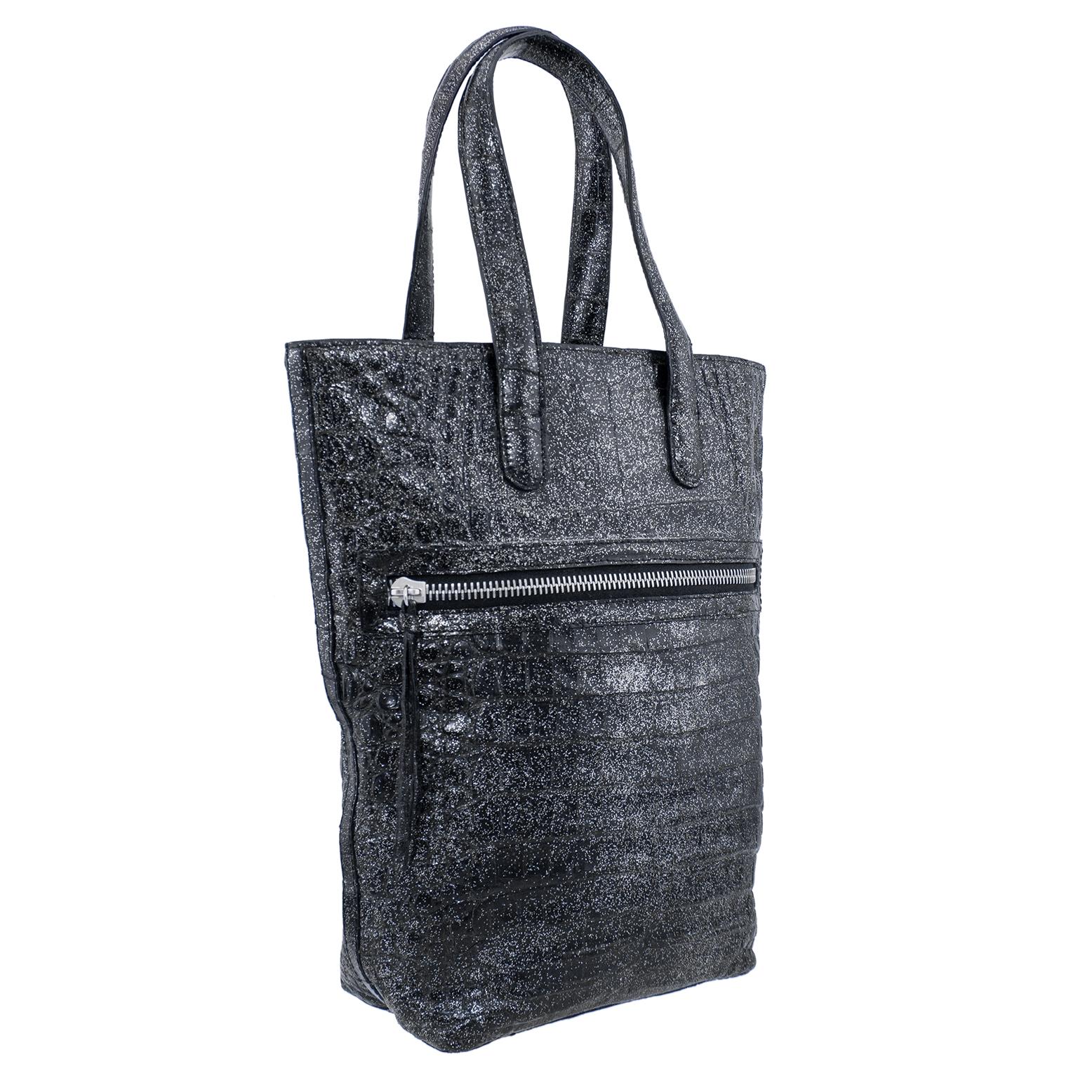 Beautiful small anthracite tote by Colombian/American designer Nancy Gonzalez. Black with an all over dusting of silver sparkles, gives this bag a festive metallic feel. Tall and narrow with 2 top handles and an exterior slit pocket with heavy duty