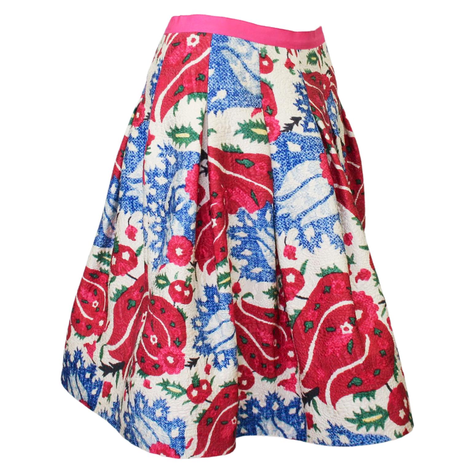 Early 2000s Oscar de la Renta flared skirt with a blue and red bold all over floral print. The skirt has a hot pink grosgrain ribbon waistband and zips up the back. The textured cotton/viscose matelasse fabric has some weight to it but is also light