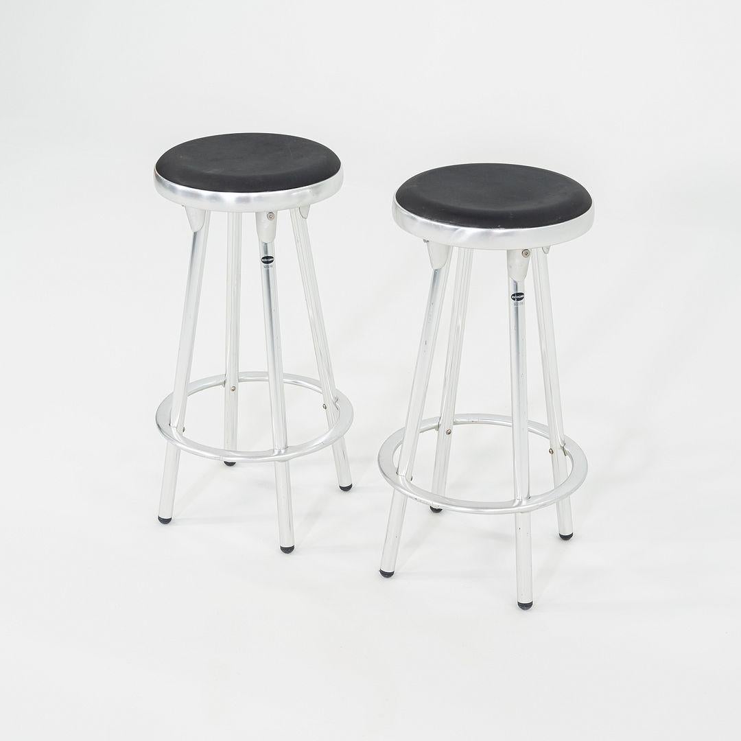 This is a pair of Indecasa Aluminum counter stools, originally designed by Joan Casas. These particular pieces were produced by Design Within Reach in the 2000s. The stools are comprised of an aluminum frame and a molded plywood seat. 

The listed