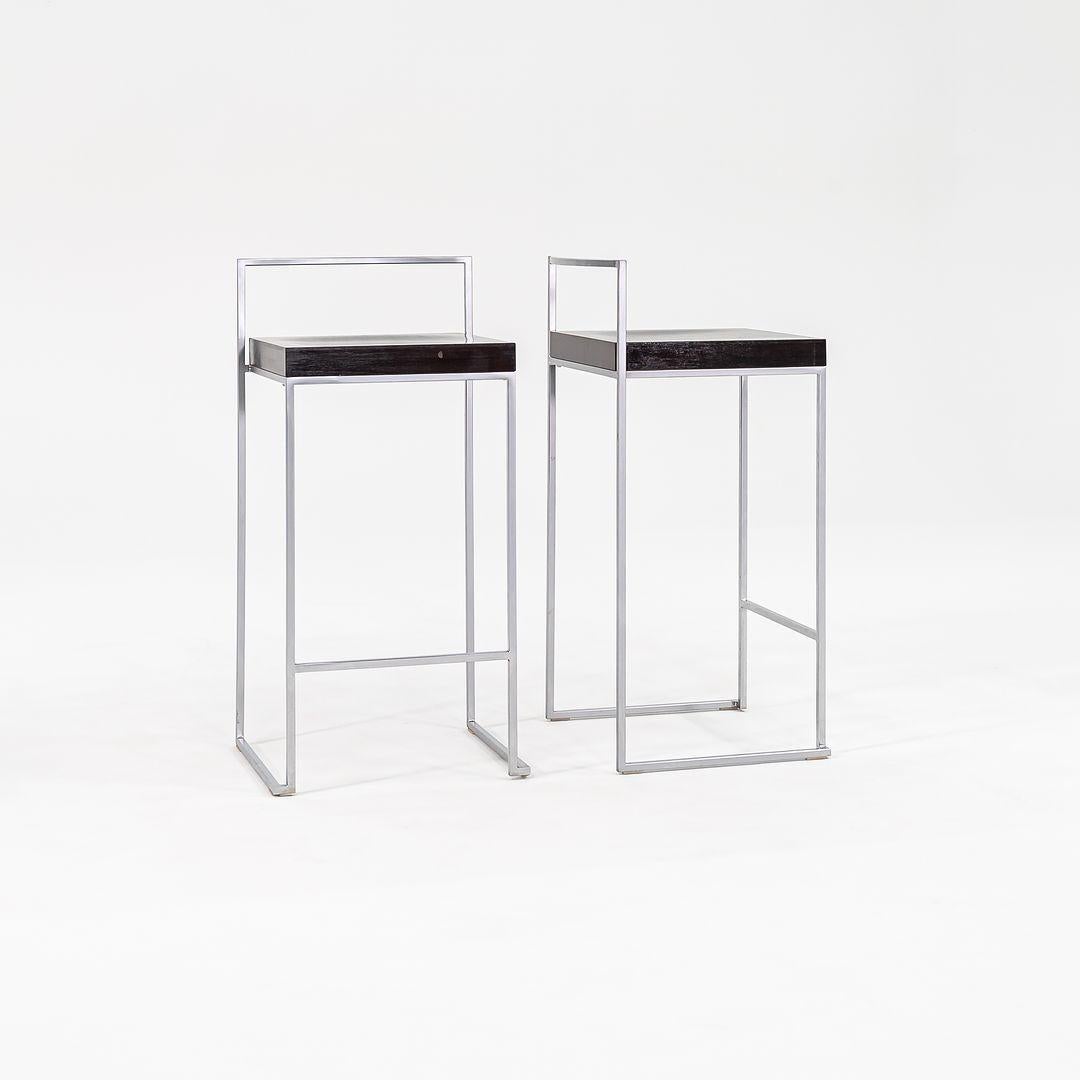 Se trata de un par de taburetes de mostrador Cubo S62, diseñados originalmente por Enzo Berti en 1998. Estos ejemplares en concreto fueron fabricados por Lapalma en Italia en la década de 2000. Los taburetes se componen de un asiento de haya nogal