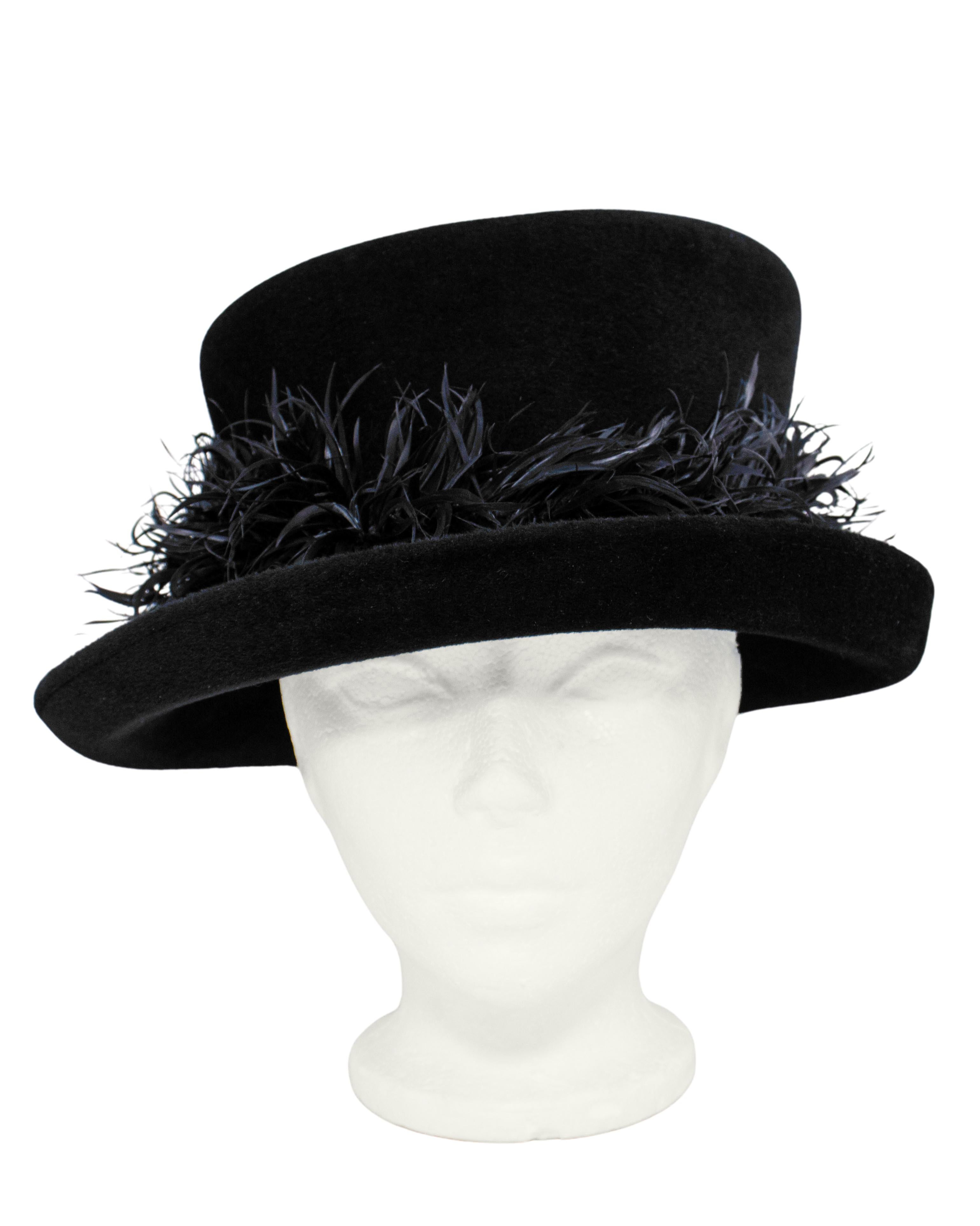 Cappello asimmetrico in feltro nero di Philip Treacy con bordo di piume e fodera in raso viola. Risale alla metà degli anni 2000. Il look è quello classico di Treacy, con un senso dell'umorismo e allo stesso tempo pratico per essere indossato in