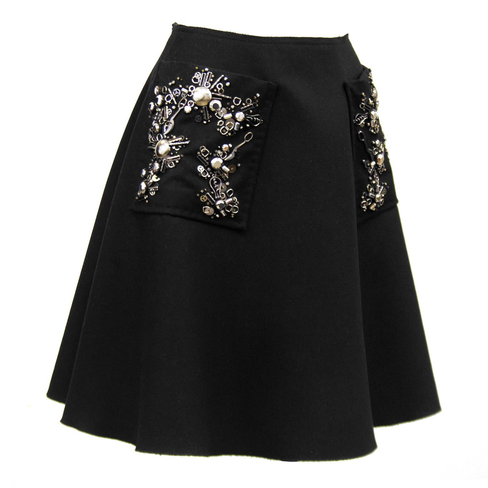 Prada black wool high waisted full A-line skirt from the early 2000's. Large patch pockets with classic silver and black Prada beaded embellishment and raw hem. Invisible zipper up centre back seam. Perfect with a black turtleneck, black tights and