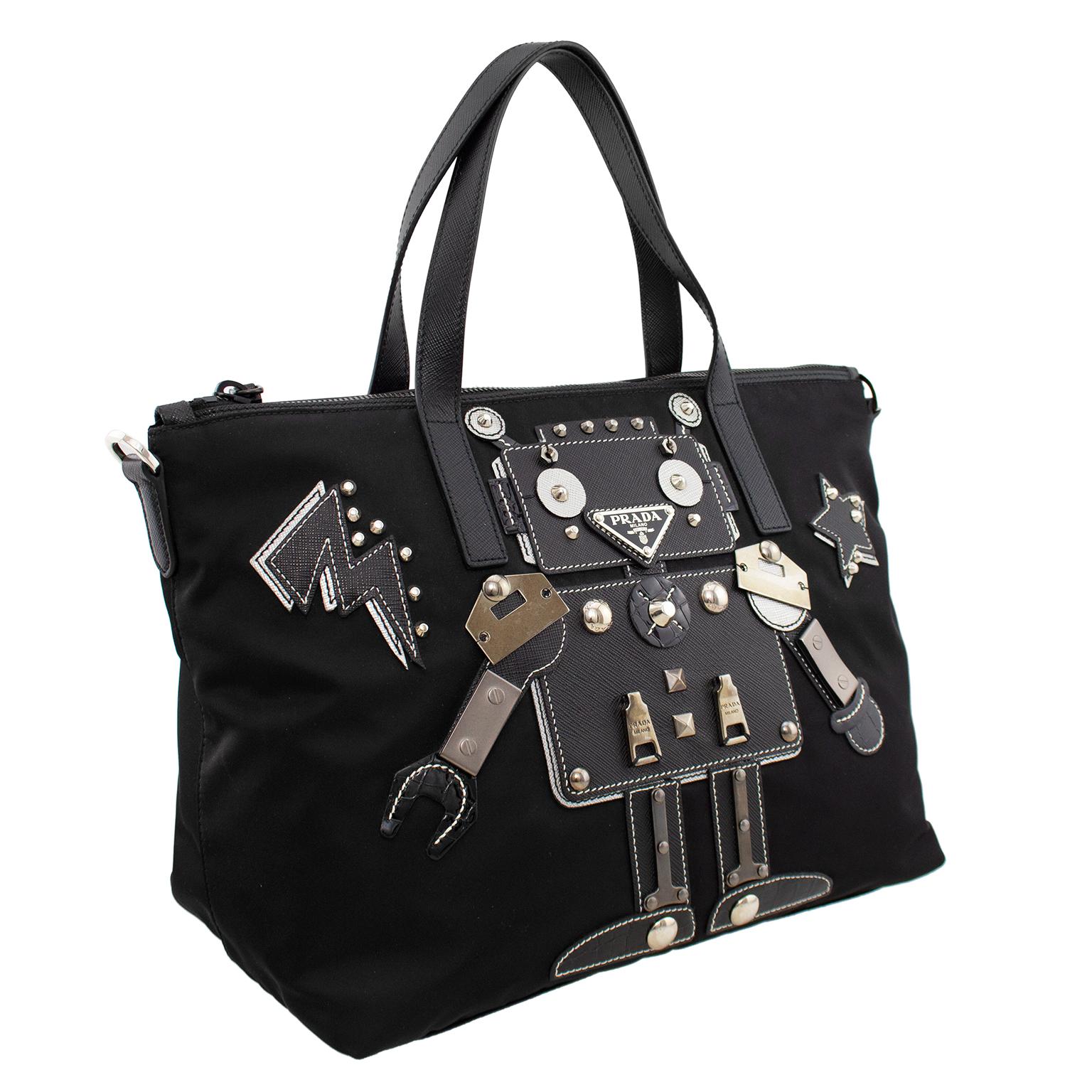 Very fun and cute Prada bag from the early 2000s. Black nylon with two black leather short top handles. The front is embellished with a large robot, made out of scraps from the Prada atelier. The body of the robot is made from black and silver