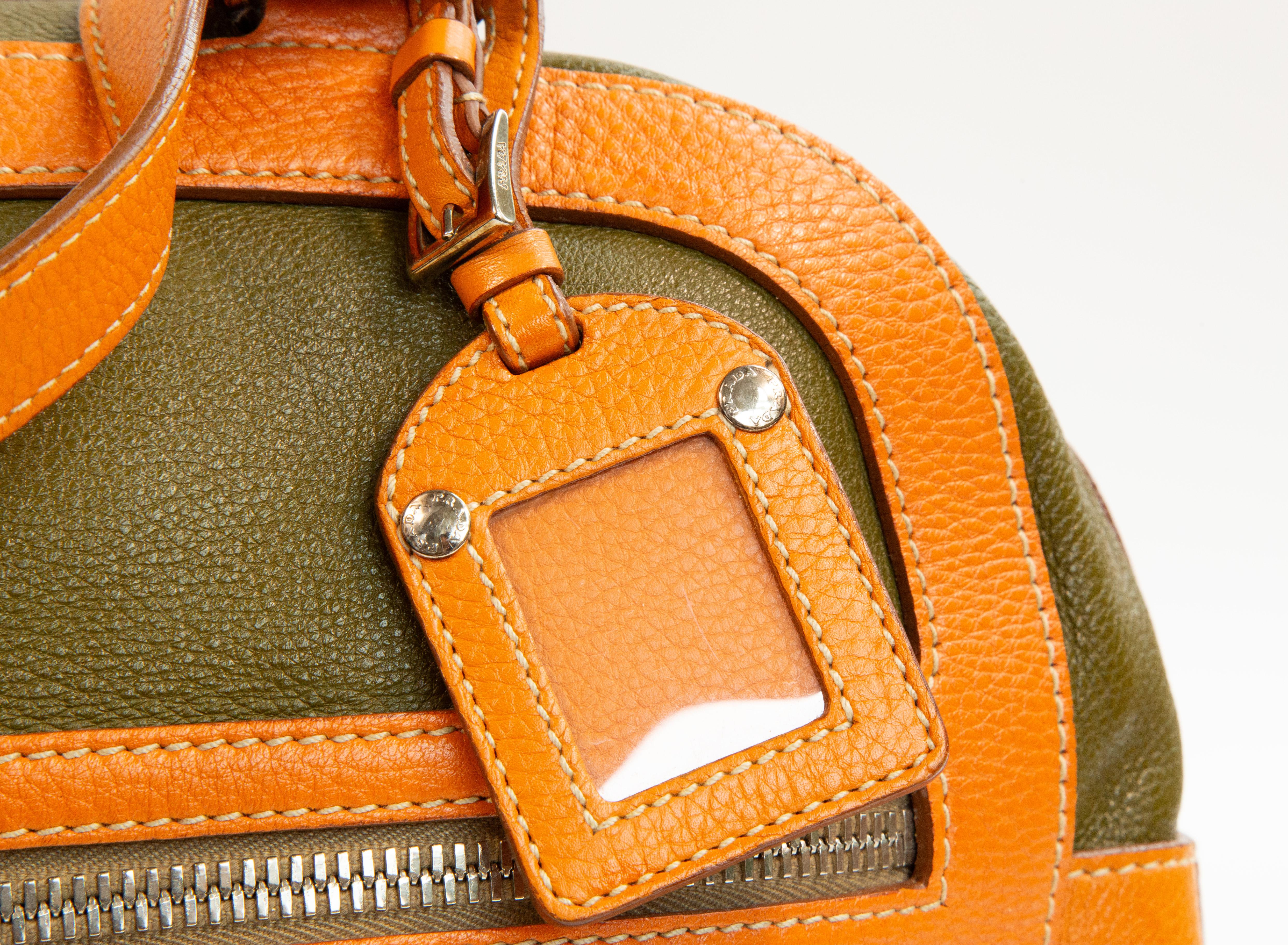 Prada shoulder bag made of green and orange leather with silver toned hardware. The bag is lined with orange fabric with Prada logo, and next to the major compartment it features two pockets with a zipper. The bag closes with two zippers. The bag