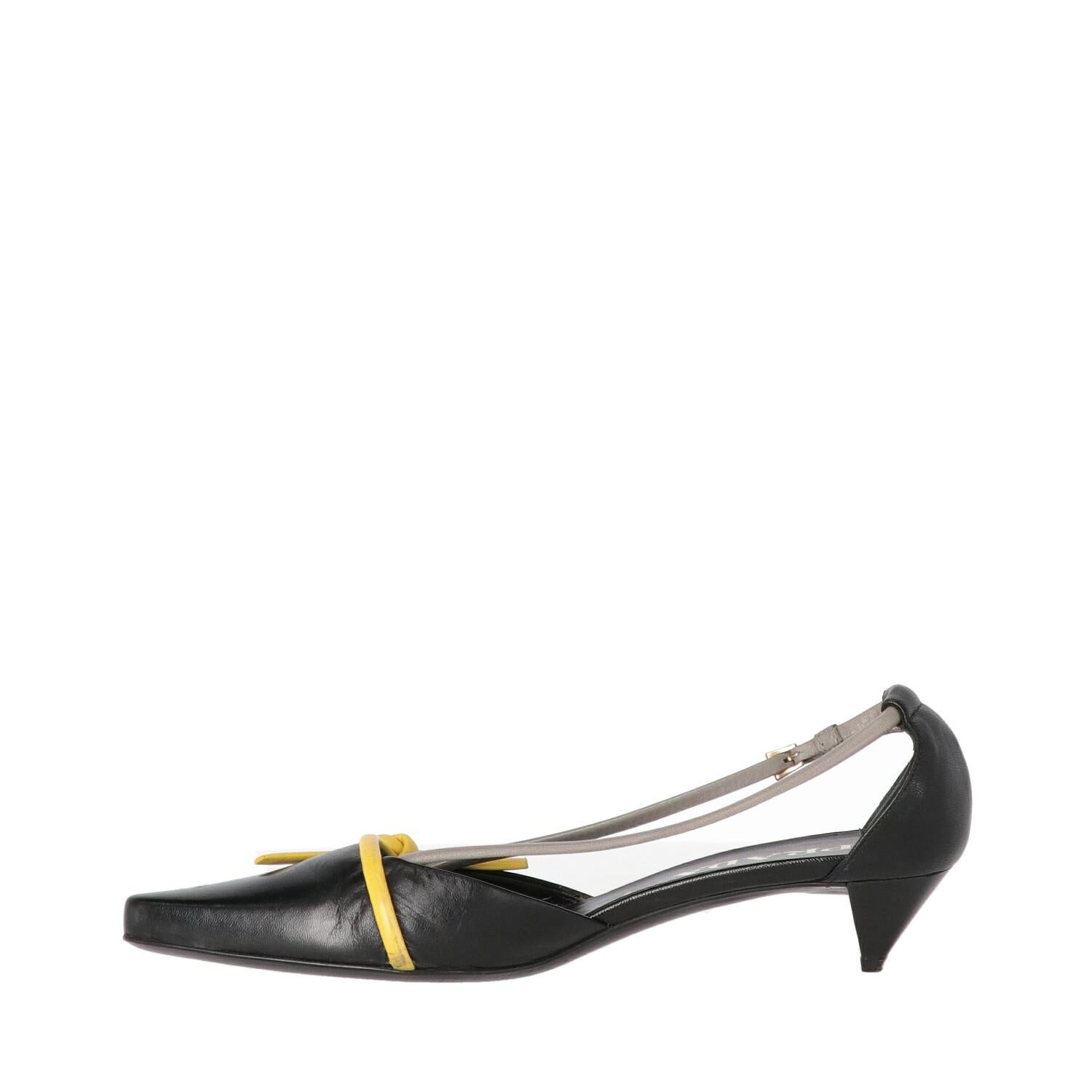 Prada black leather shoes. Kitten heel model, blunt toe and yellow decorative knot. Leather strap, metal buckle and logoed leather insole.

The shoes show some wrinkles and signs of wear on the leather, as shown in the pictures.
Years: 2000s

Made
