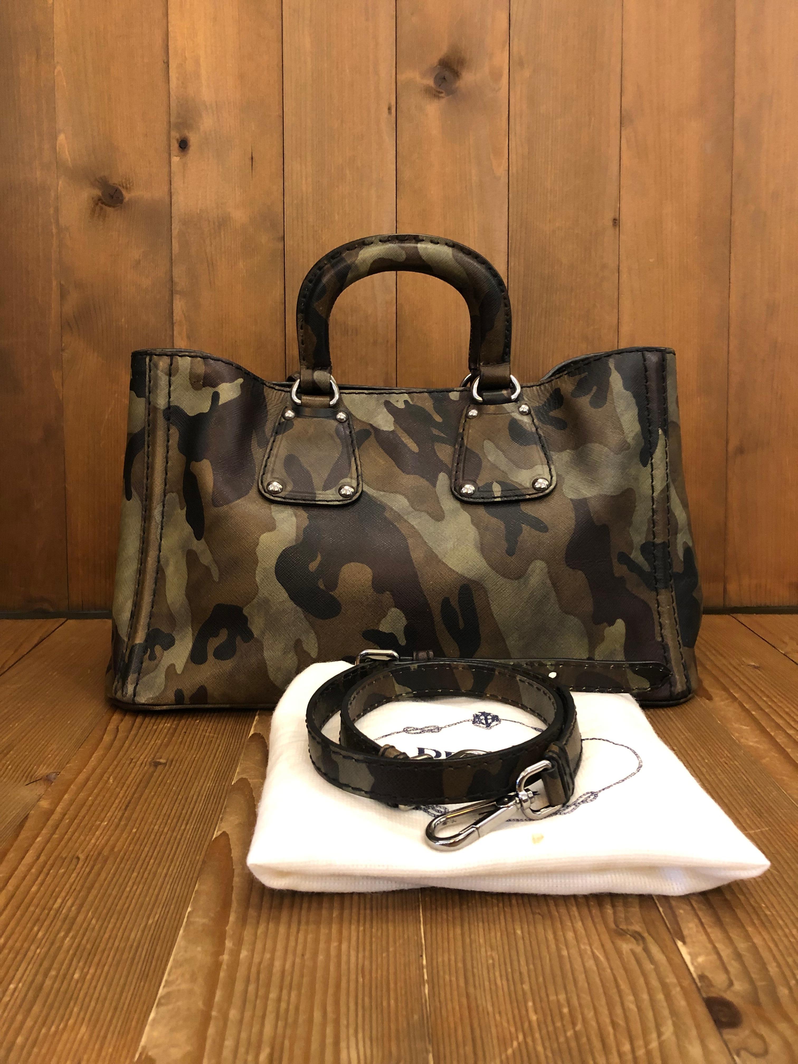 2000s Prada two-way tote in green camouflage Saffiano leather featuring shiny silver-toned hardware and sturdy handles along with detachable shoulder strap. Made in Italy. Measures approximately 15 x 9 x 8 inches handle drop 17 inches at its