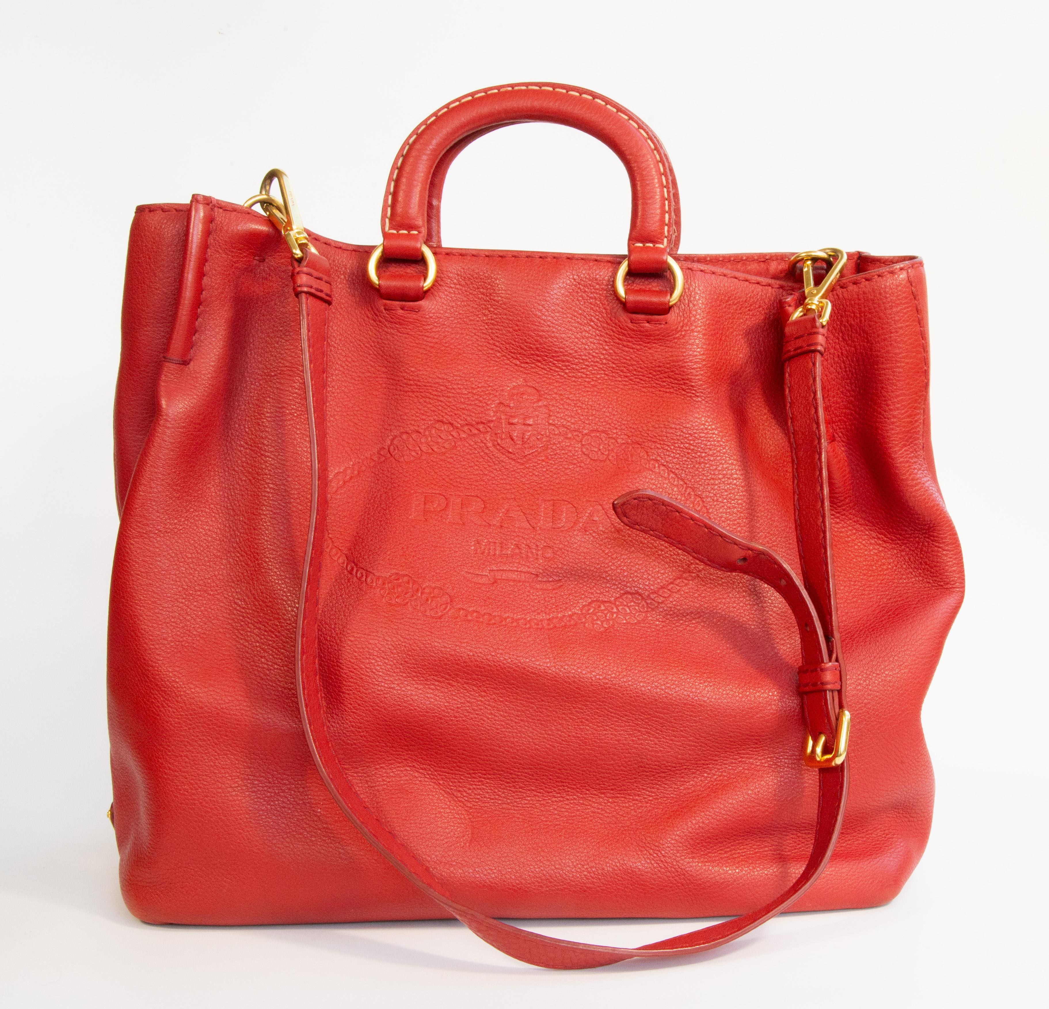 Prada Tote/2-Wege-Tasche, die sowohl als Henkeltasche als auch als Schultertasche/Crossbody getragen werden kann. Die Tasche ist aus rotem Leder mit goldfarbenen Beschlägen gefertigt. Das Innere ist mit rotem Synthetikstoff mit Prada-Logo