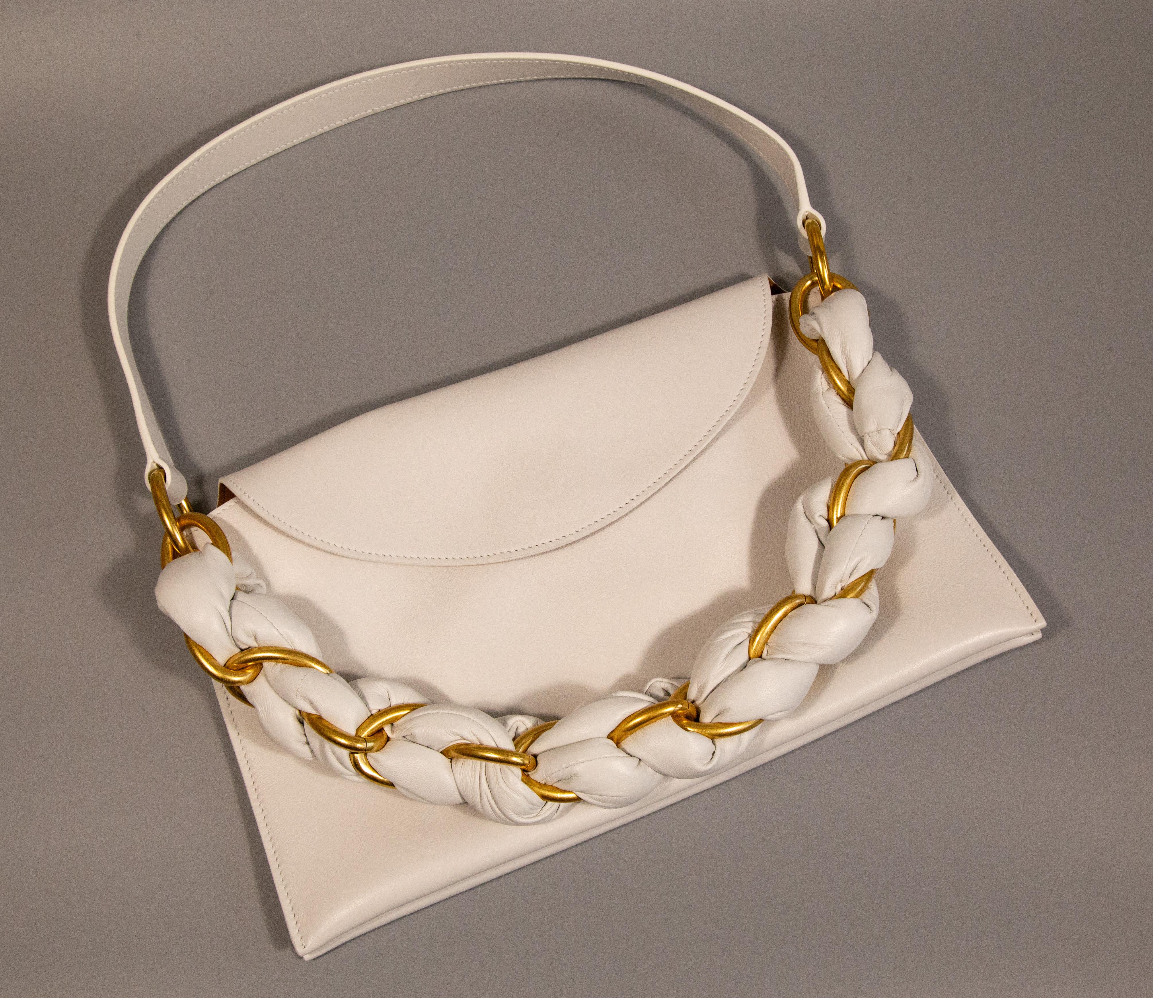 A shoulder bag designed by Proenza Schouler. The bag is made of white calf leather with gold toned hardware. The interior is lined with suede and next to the major compartment it features three slide pockets. The bag closes with a magnetic button.