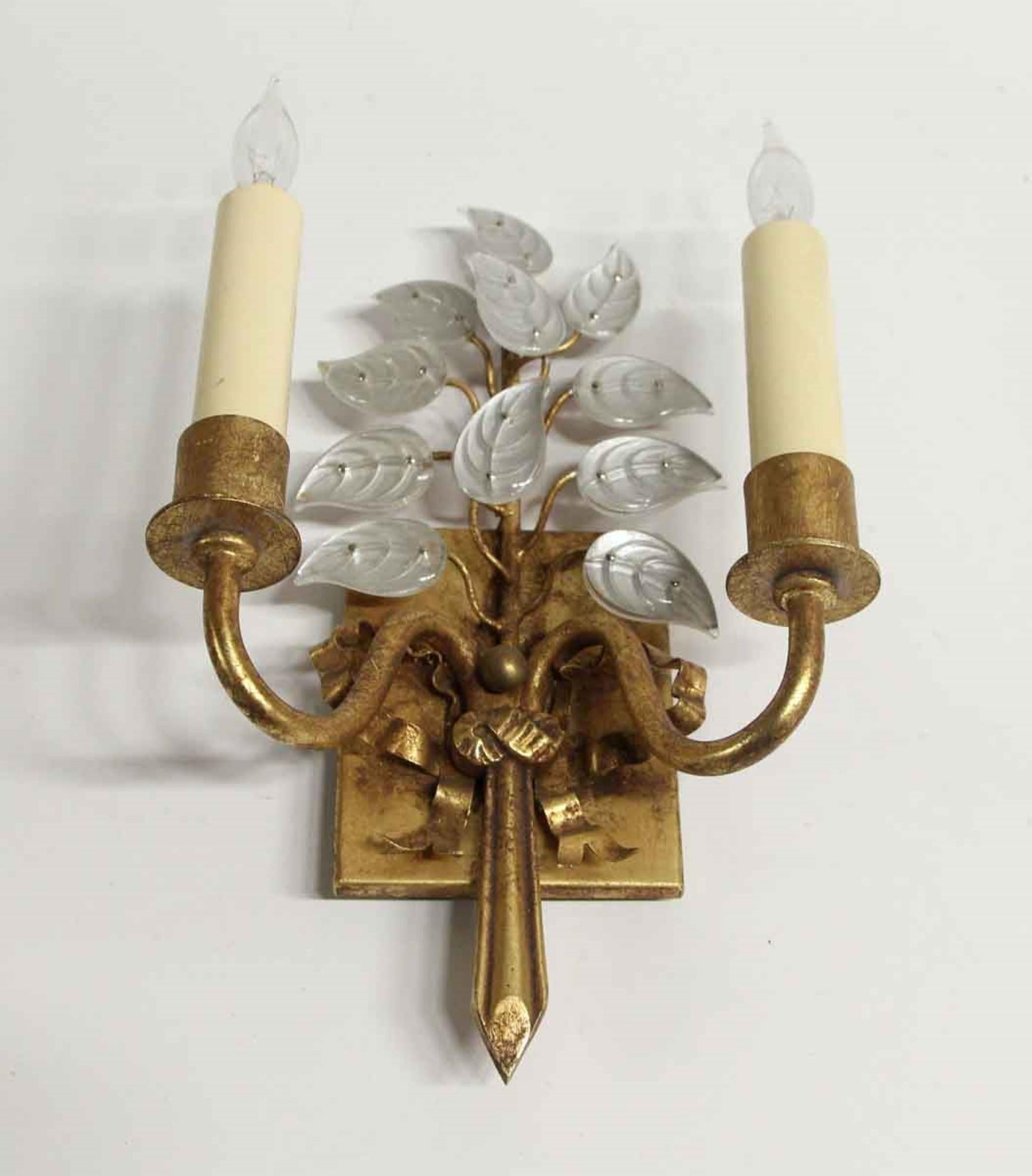 2000s Baguès style gilt gold and iron two-arm petite sconce featuring crystal leaves with a ribbon motif back plate. This is not a genuine Baguès. This can be seen at our 400 Gilligan St location in Scranton. PA.