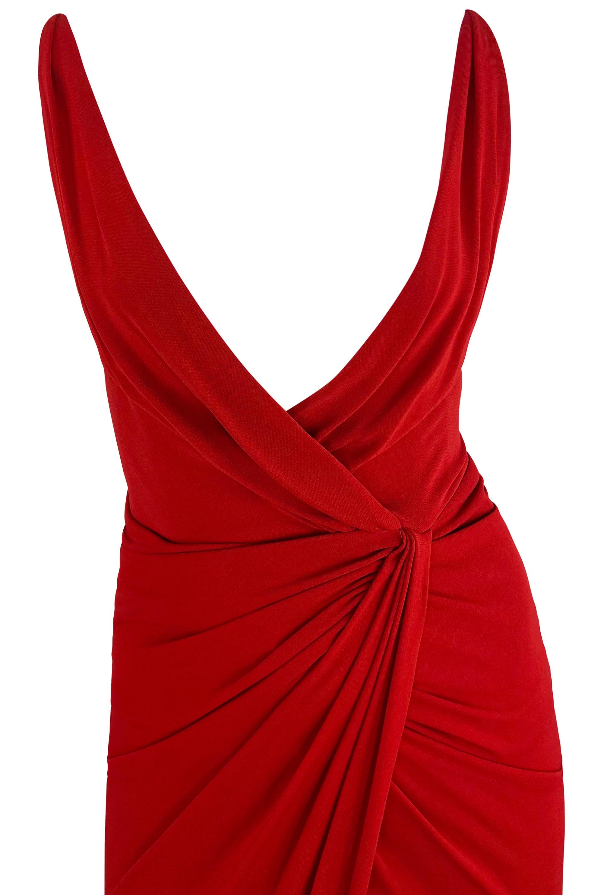 From the early 2000s, this Randolph Duke wrap-style gown is an ultra-sexy addition to any wardrobe. This bright red dress features a faux wrap style that pinches at the waist. This sultry dress features a deep, plunging neckline, an exposed back, a