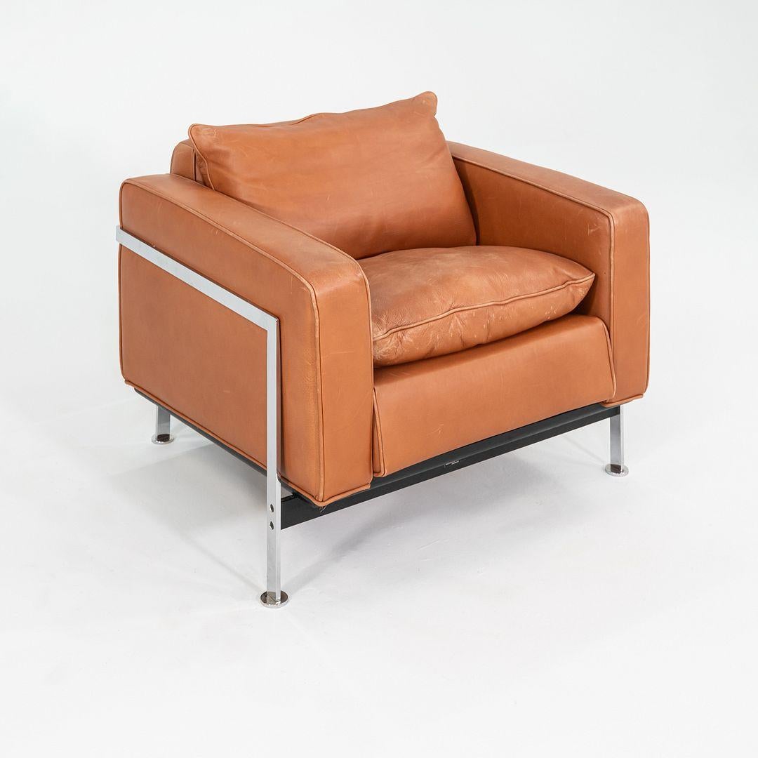 This is a RH 302 arm chair, originally designed by Robert Haussmann in the 1950s. This particular example was produced by Nienkamper in Canada in the 2000s. The chair's design features a chrome-plated steel frame and is upholstered in a brown