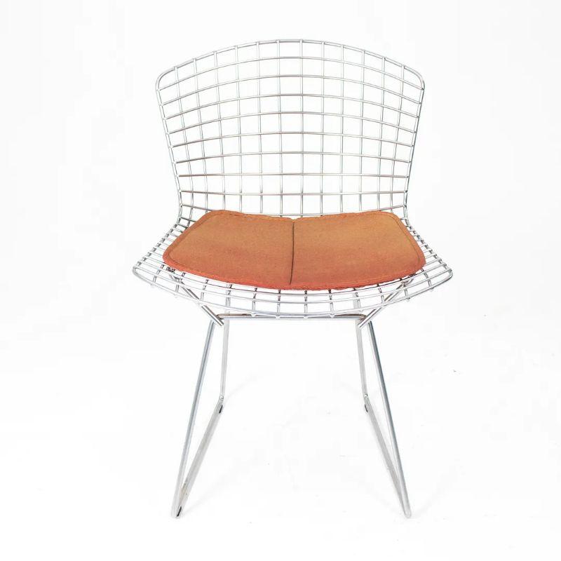 These are classic Bertoia side chairs, model 420c, designed in 1952 by Harry Bertoia for Knoll International. These chairs consist of welded chromed-steel wire seats & backs, and retain their original orange seat pads. These date to circa mid 2000s
