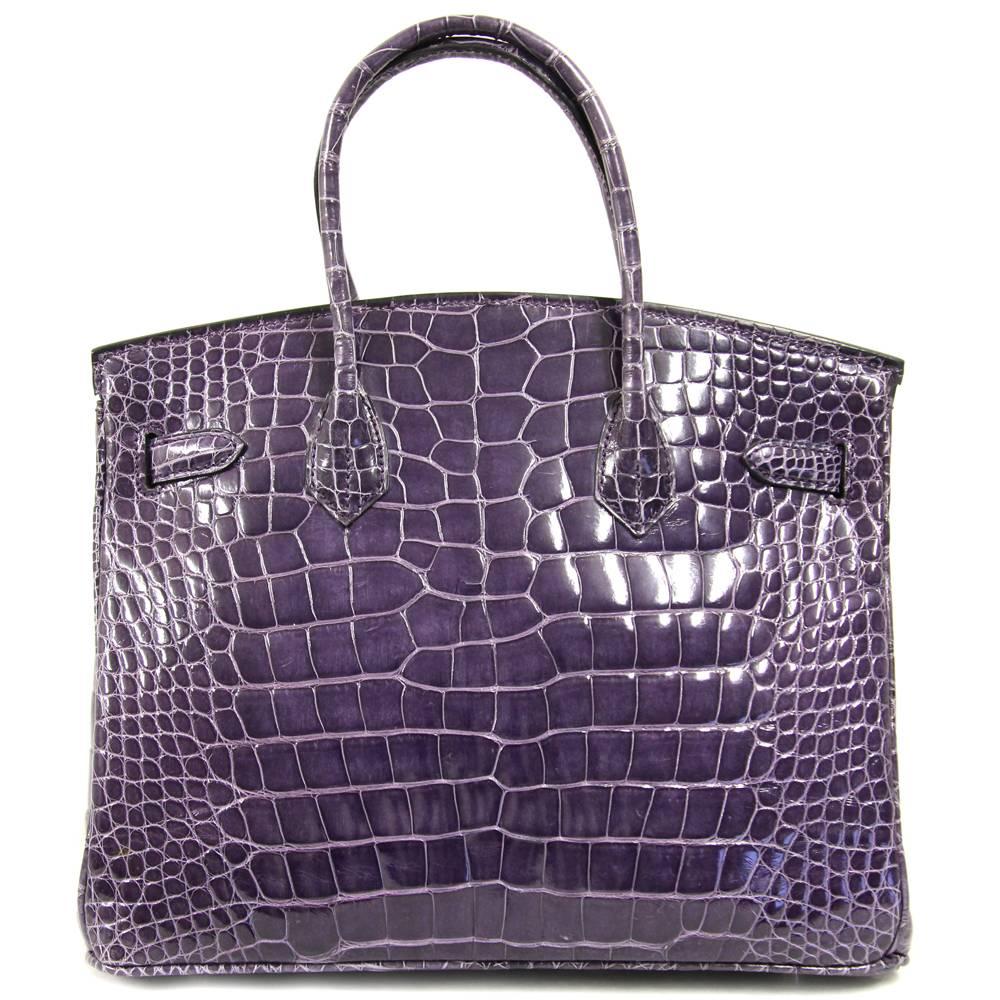 Purple bag in crocodile leather made by Sirni, guarantee of italian quality handmade leather goods. The item comes with padlock, keys and clochette. The item is in good conditions, it shows light signs of utilization on the hardware and on the inner