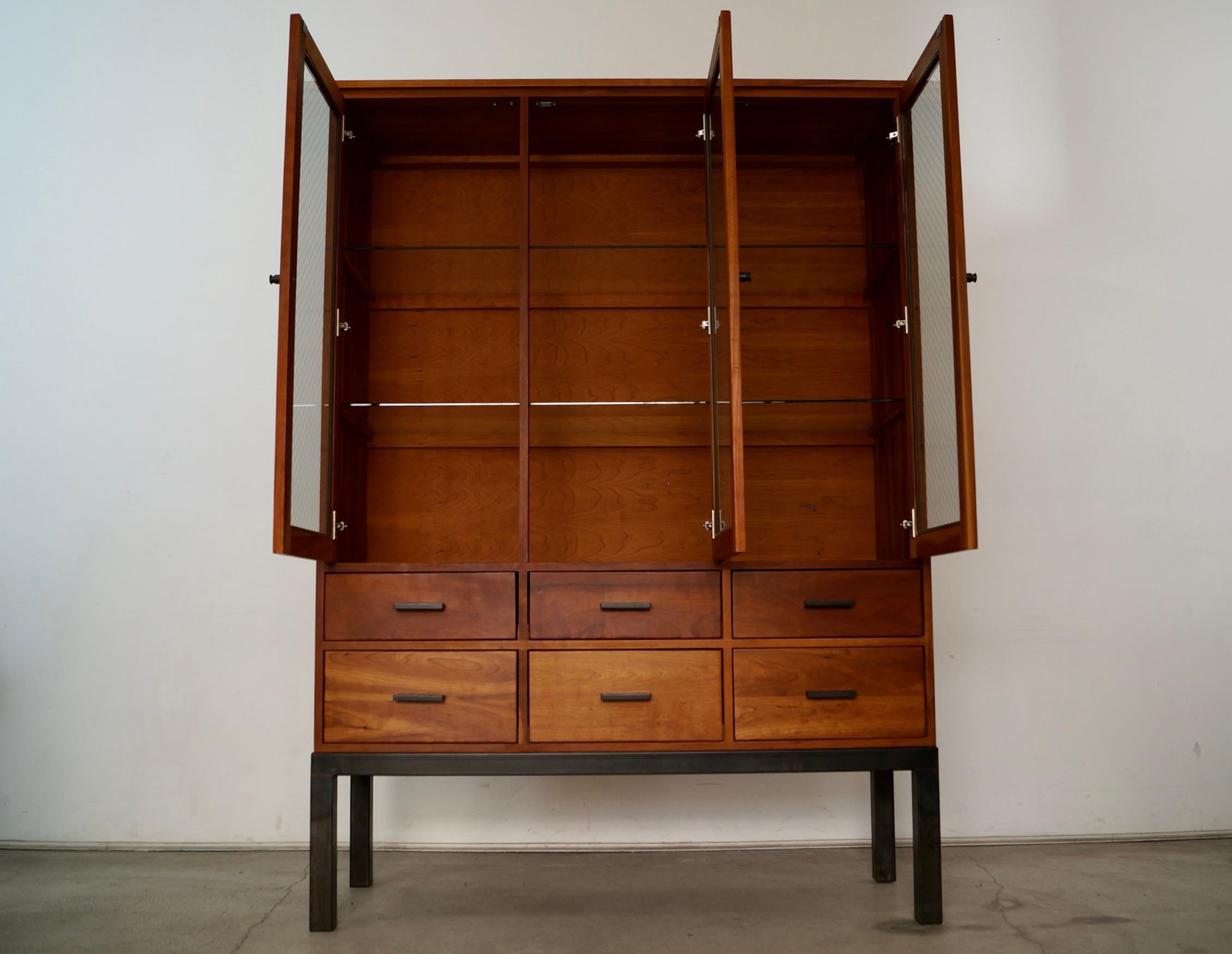 vVintage solid cherry china cabinet hutch for sale. It was manufactured here in the US by Room & Board, and is a very high-quality designer piece. It's made of solid cherry in a natural cherry finish. It has a contemporary industrial blended with