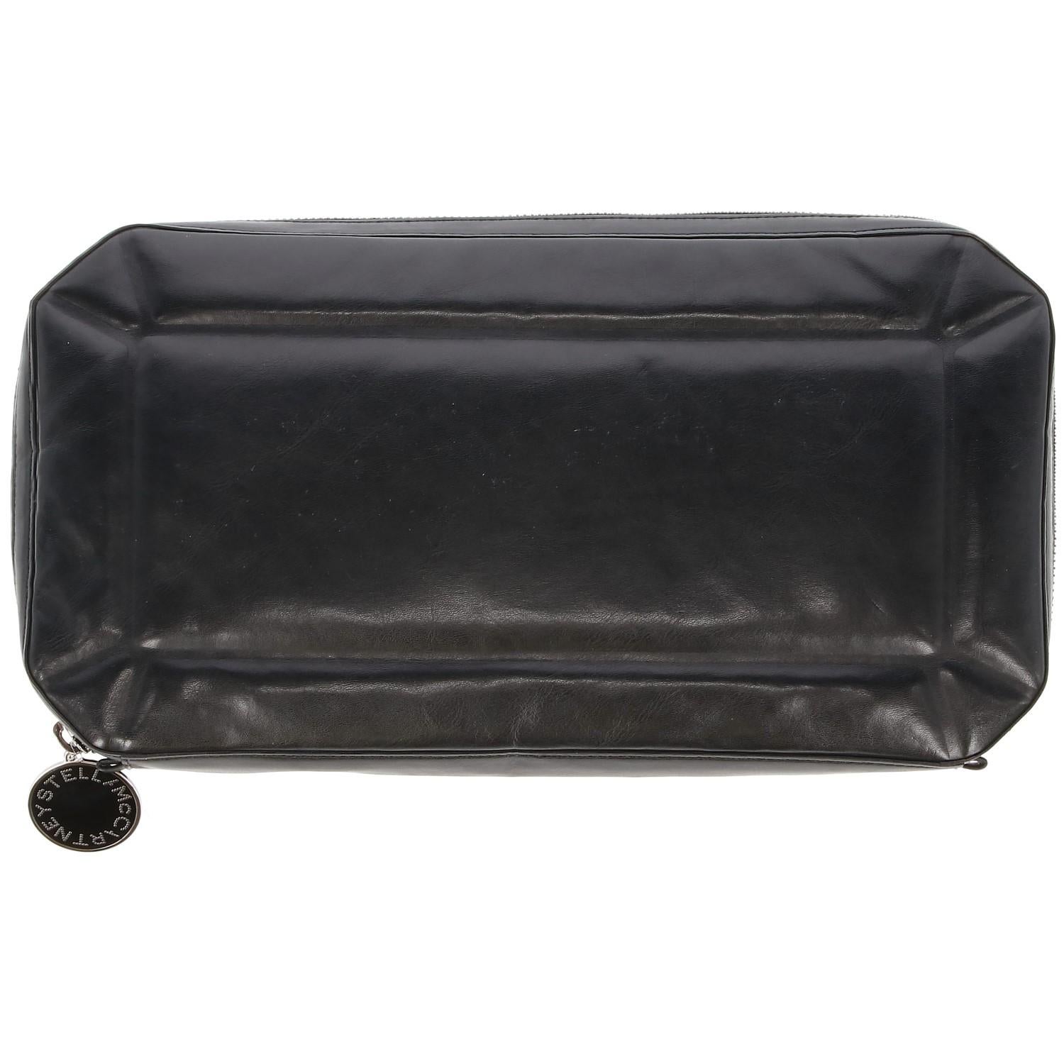 The stylish Stella McCartney black faux leather geometrical shape clutch is lightly matelassé, with elegant purple lining and zip- fastening with black and silver-tone round branded pendent. The bag shows some stains at lining, as shown in the