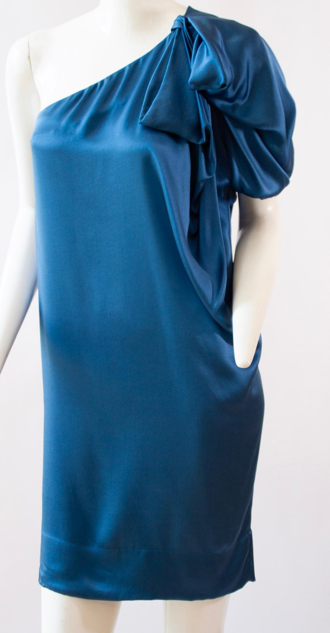 Azure blue silk dress from Stella McCartney. Bow detail and draping at shoulder. Sack style narrowing hemline. 

Size 34

100% Silk