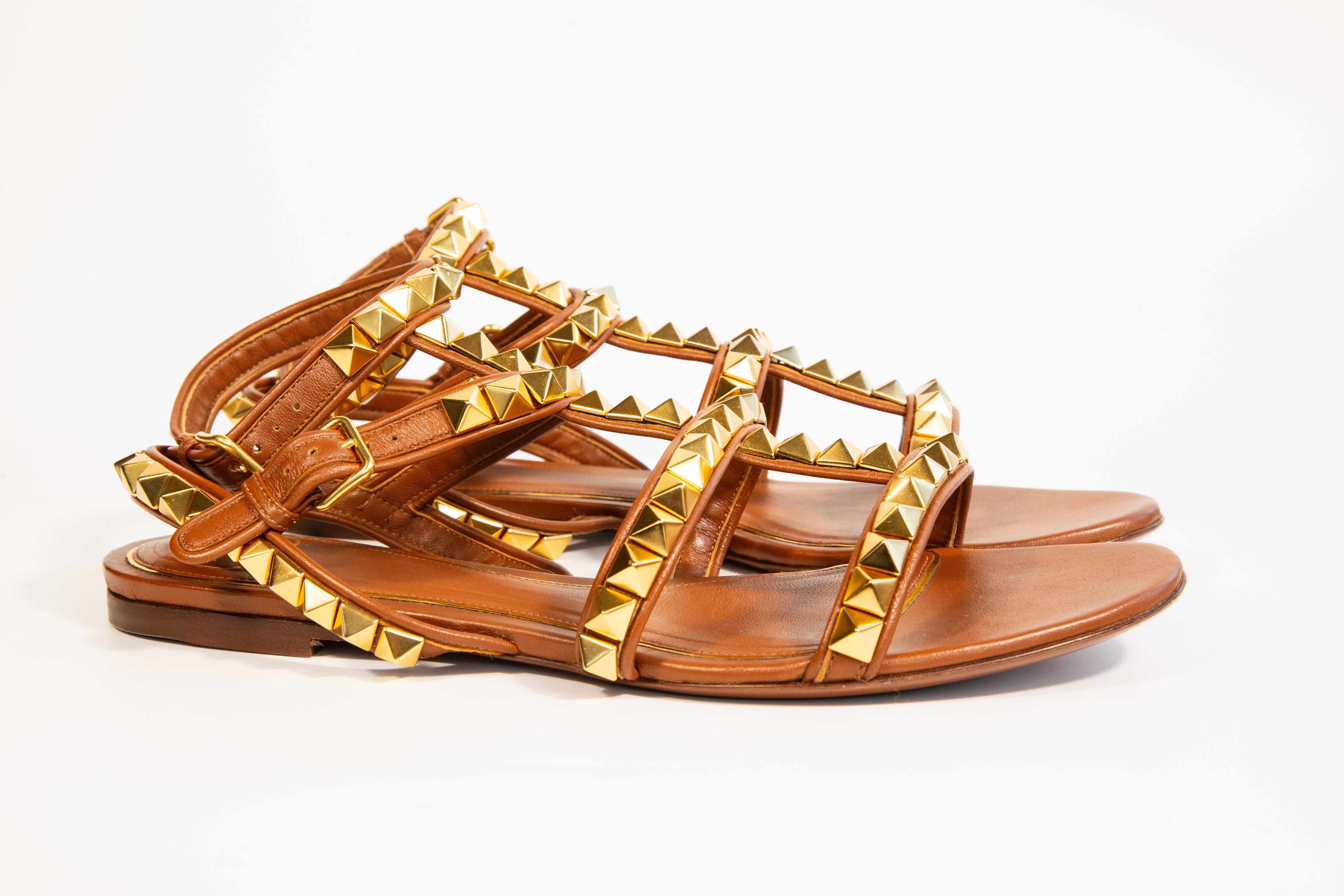 Sandalias planas Valentino Garavani de piel marrón con tachuelas doradas. Nunca usada y en perfecto estado. Se entregarán con la caja de zapatos y la bolsa guardapolvo originales.  Talla EU 39. 