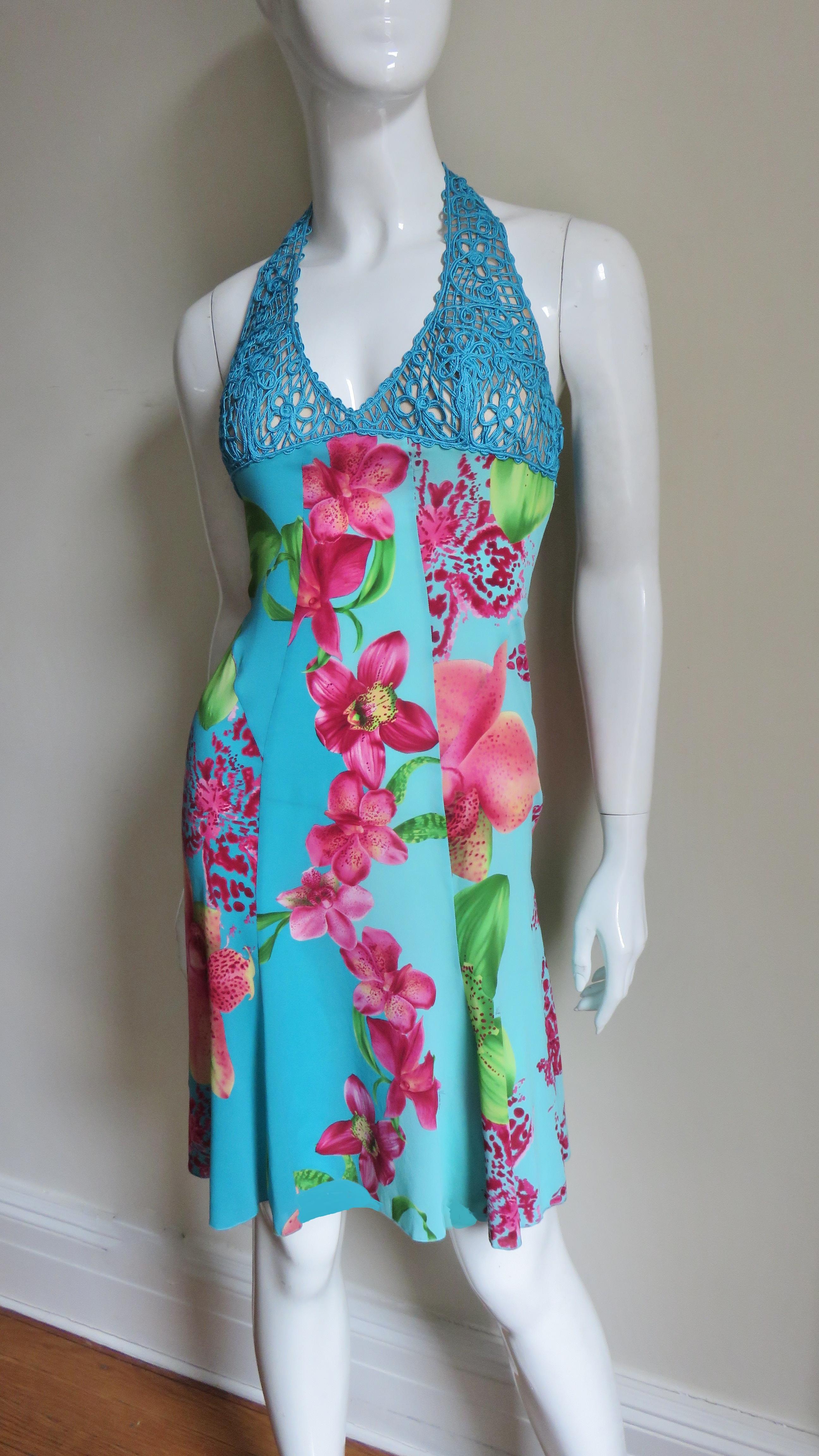 Fabuleuse robe dos nu en soie fine extensible de Versace, imprimée d'un lys rose coloré sur fond turquoise. L'encolure licou et la poitrine sont constituées de cordons de soie complexes formant un motif floral. Le corps de la robe est composé de 4