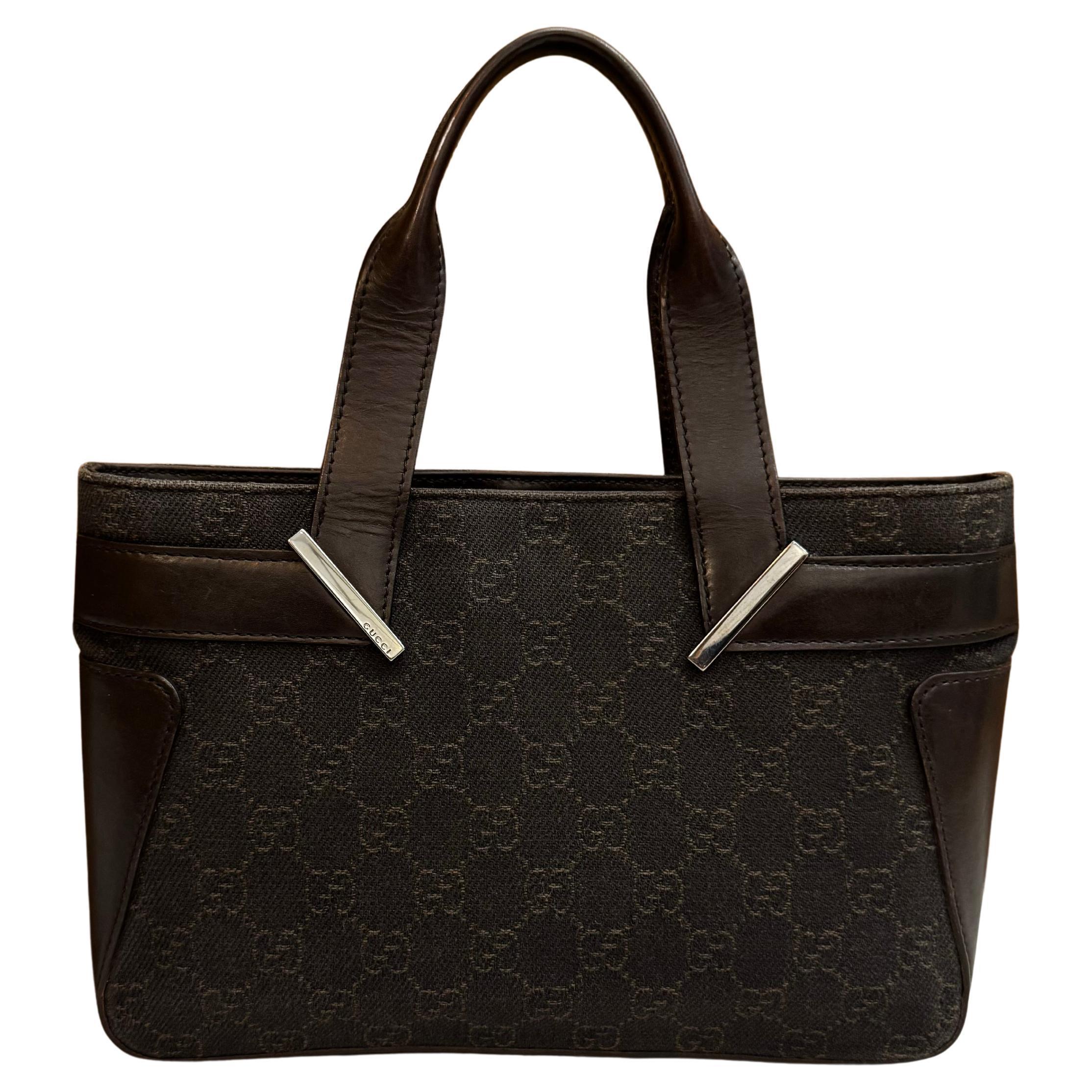 This vintage GUCCI mini tote handbag is crafted of brown GG jacquard and smooth calfskin leather featuring silver toned hardware. Handles open to a brown fabric interior with a zippered pocket. Made in Italy. Measures approximately 10 x 6.25 x 2.25