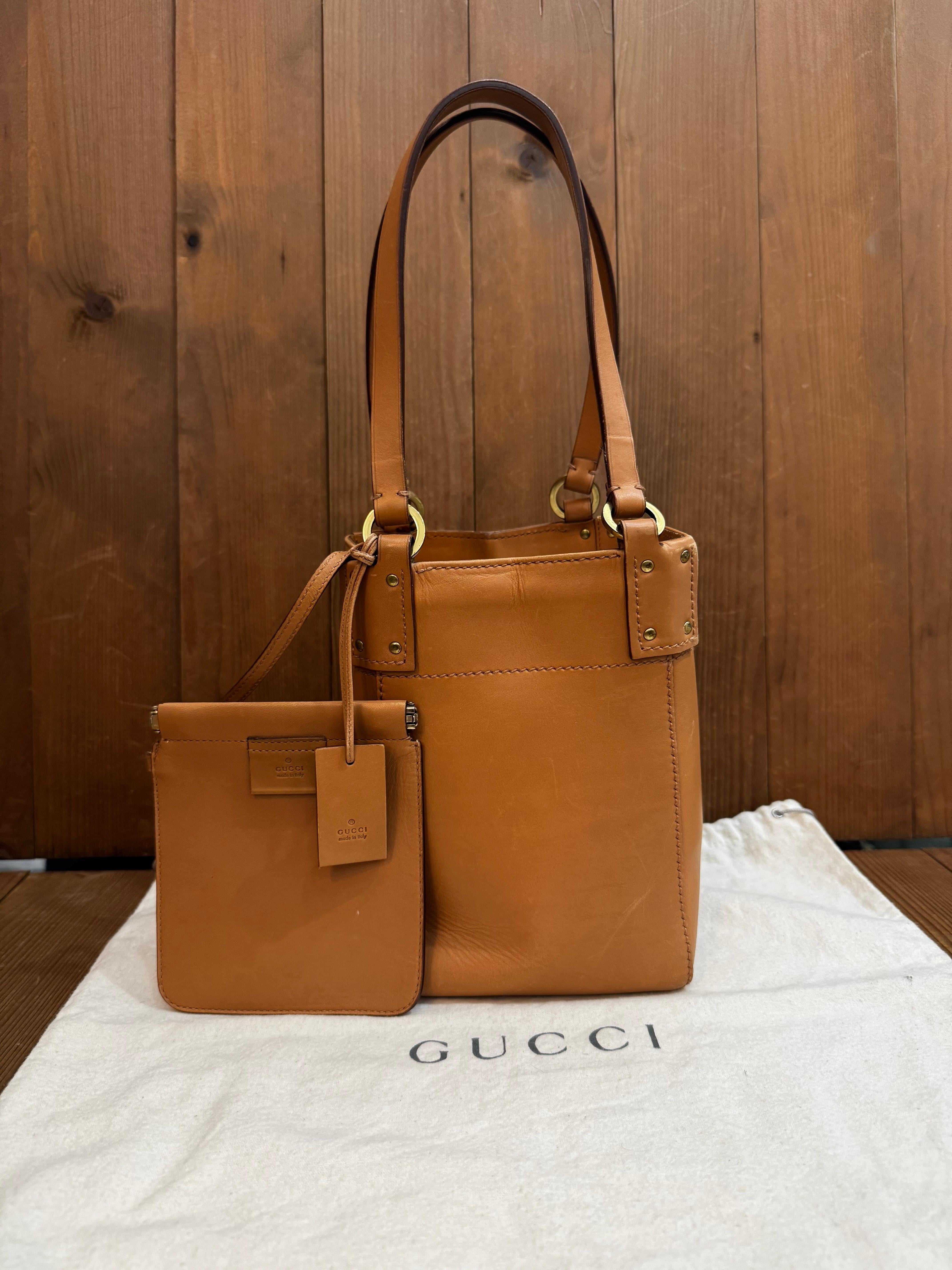 This vintage GUCCI bucket bag is crafted of cowhide leather in its natural color. Wide square top opens to an unlined interior featuring a pouch with spring closure of the same leather. Made in Italy. Measures approximately 8 x 5.5 x 5.5 inches
