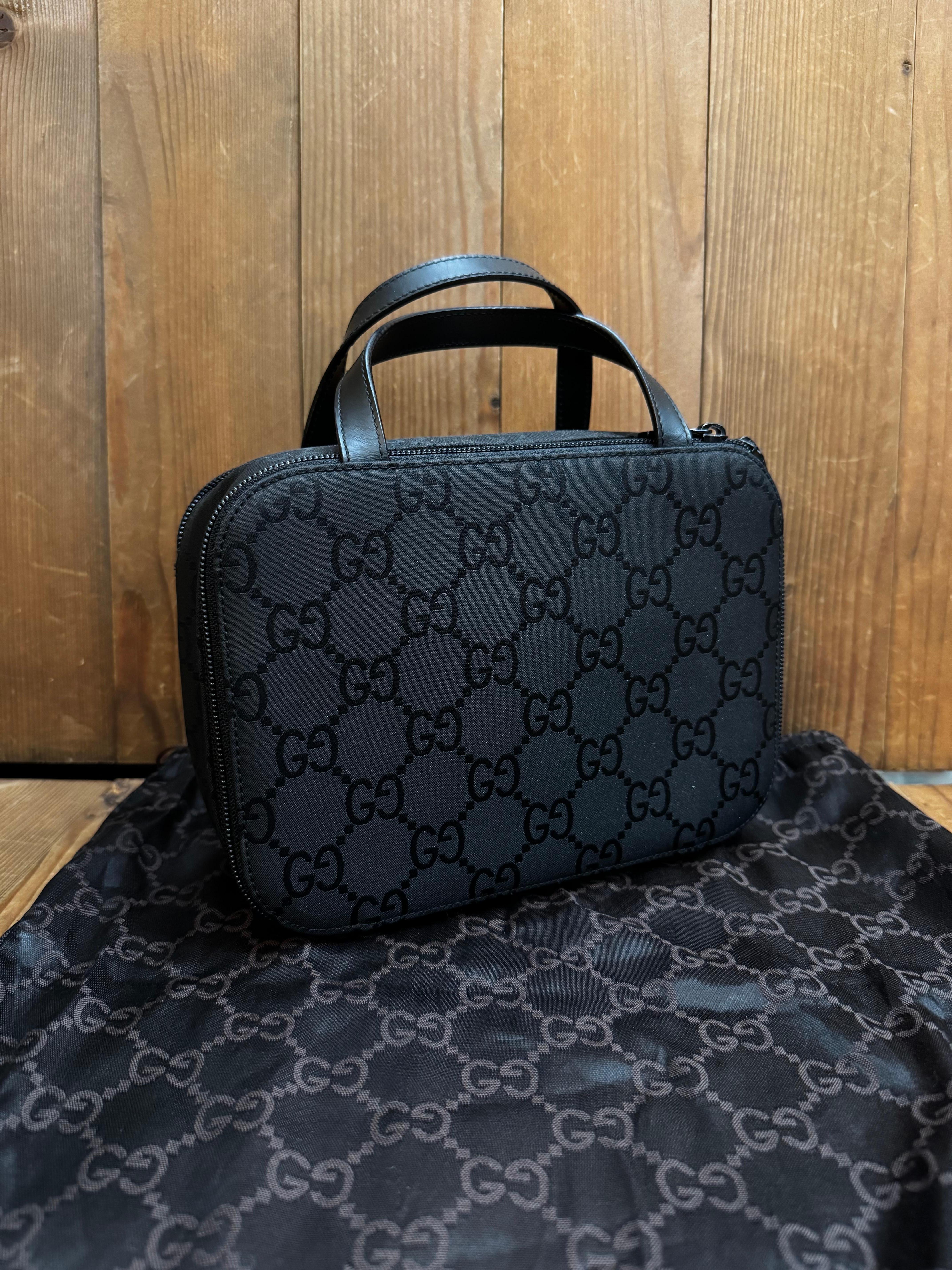 Ce sac à main vanity vintage GUCCI est réalisé en nylon noir portant le monogramme GG et en cuir de veau lisse noir. La fermeture à glissière d'un côté ouvre sur un intérieur partiellement enduit qui a été nettoyé et une partition zippée réalisée en