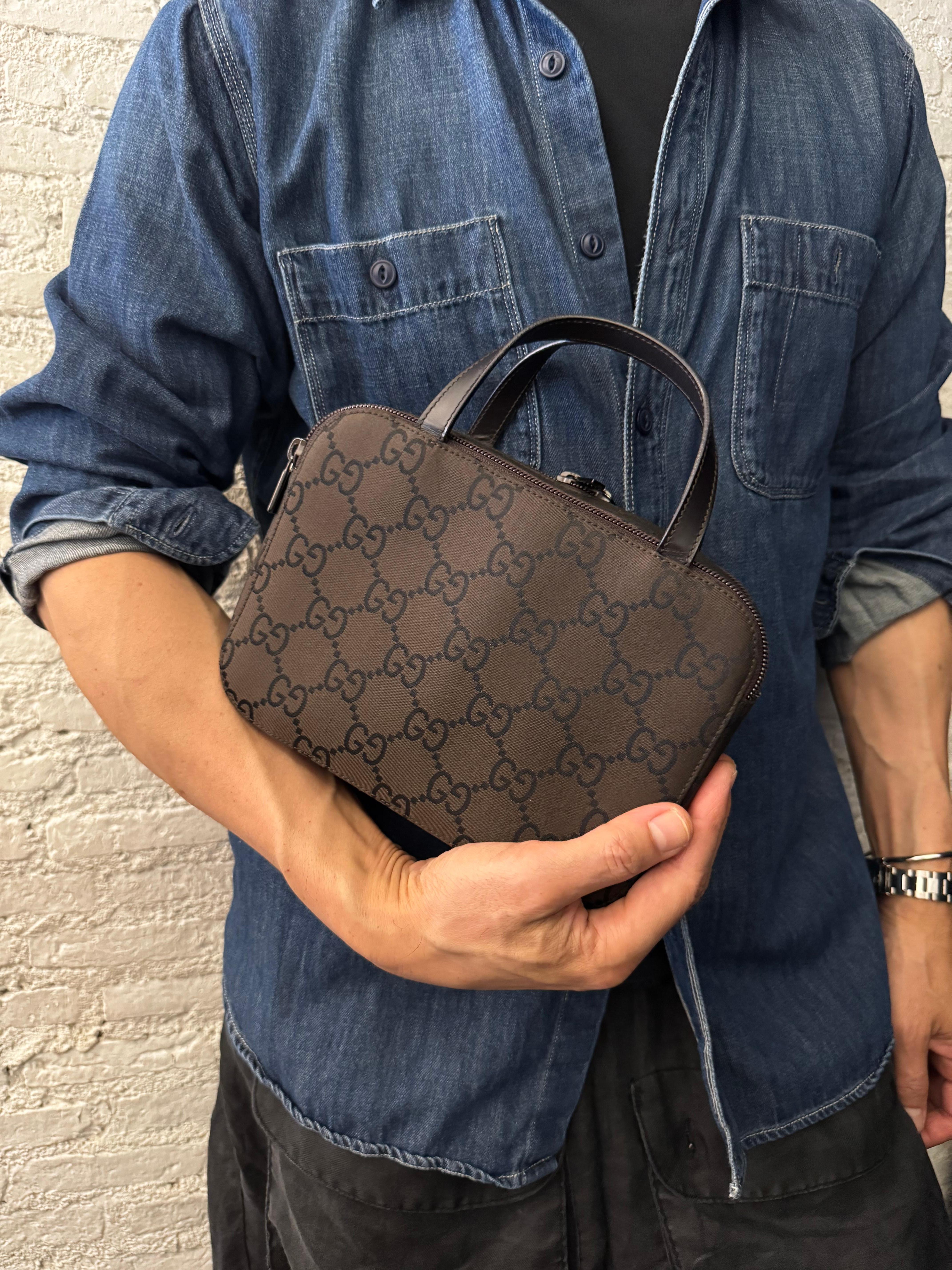 This vintage GUCCI vanity handbag is crafted of brown GG monogram nylon and smooth calfskin leather in brown. Zip around closure on one side opens to a partially coated interior which has been cleaned and a zippered partition crafted of smooth