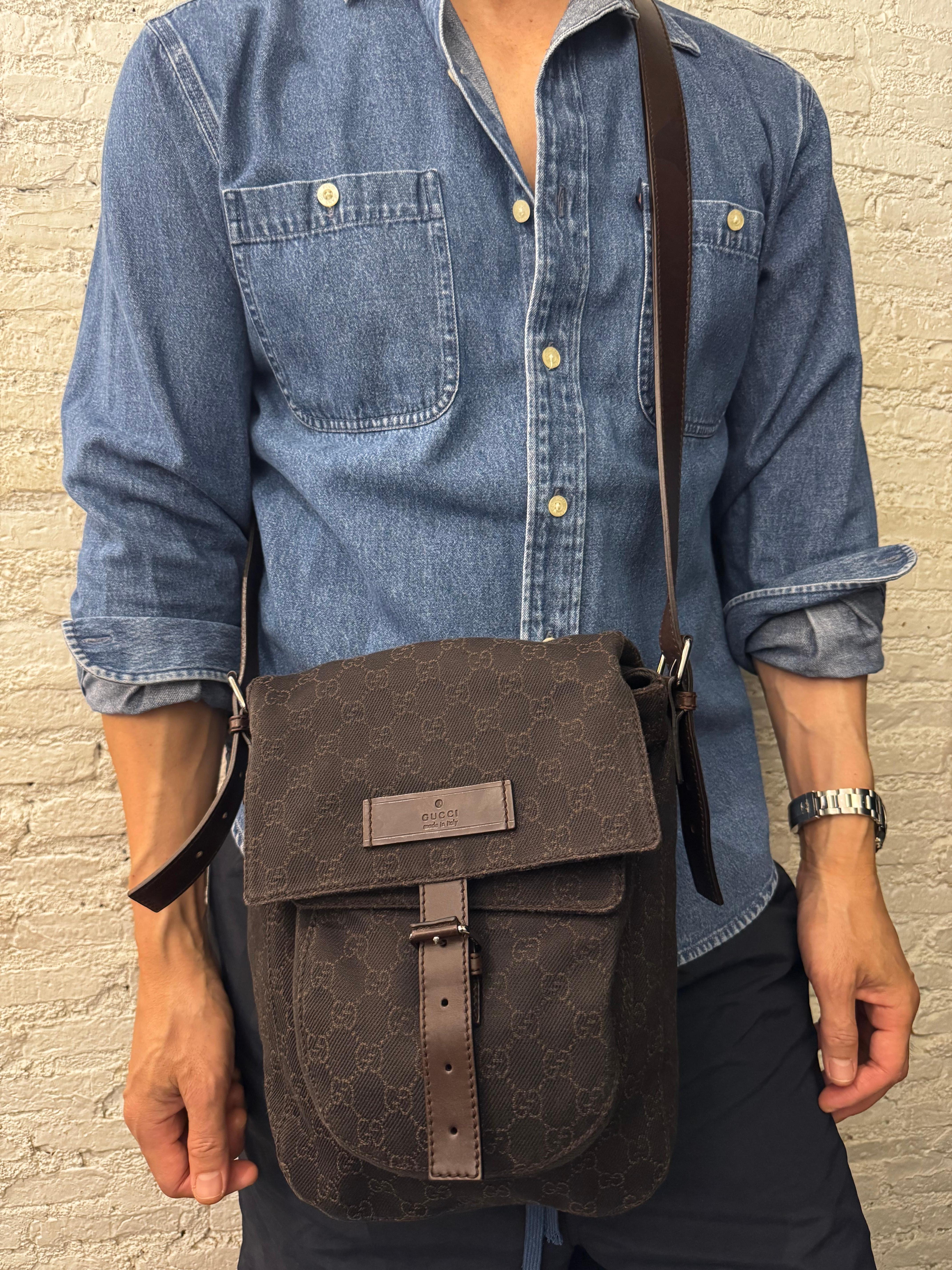This GUCCI messenger bag is crafted of GG monogram denim and cowhide leather in chocolate brown featuring silver toned hardware and a crossbody leather strap of the same leather. Front flap buckle closure opens to a brown fabric interior with a
