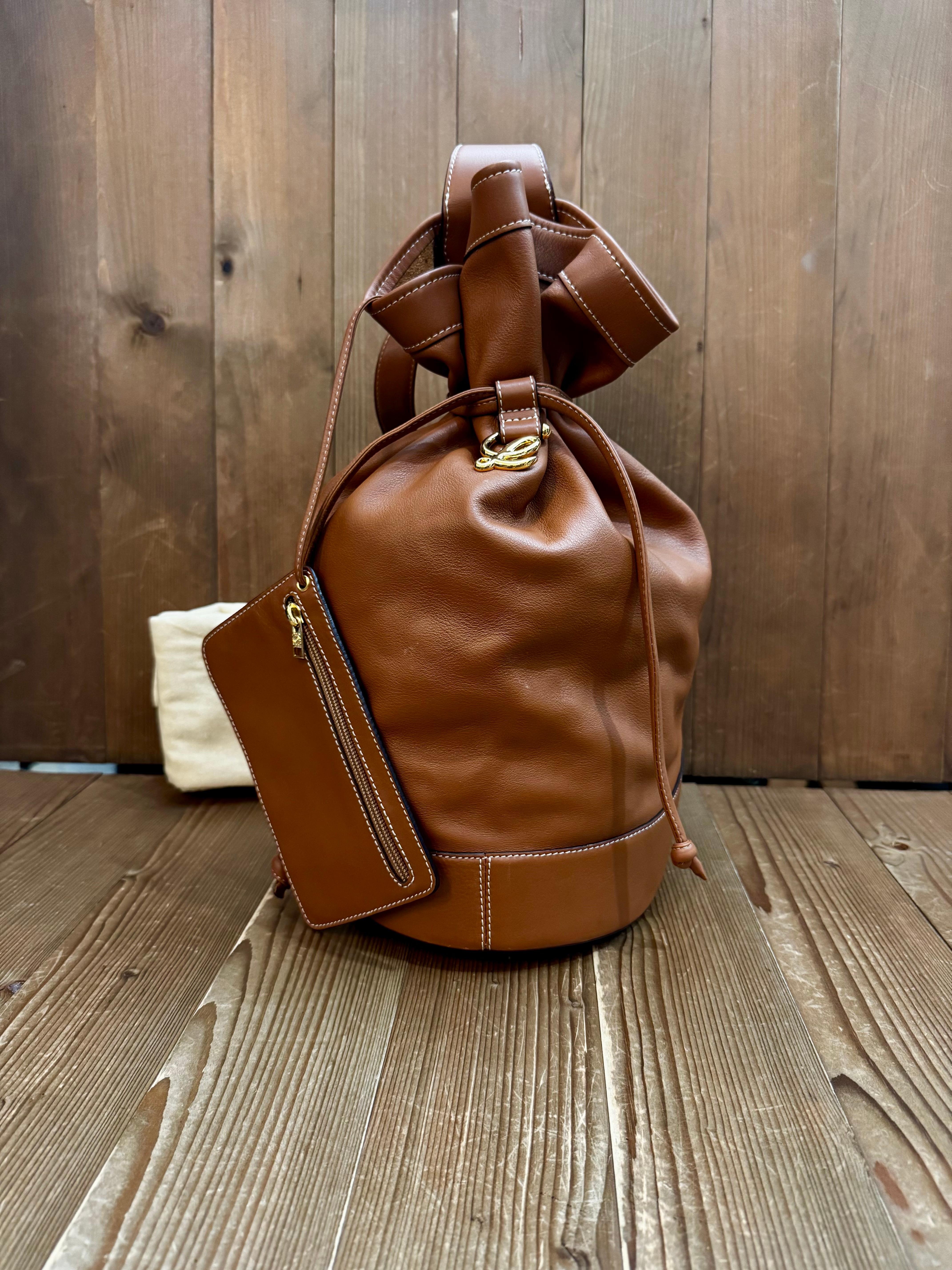 This vintage LOEWE bucket bag is crafted of soft calfskin leather in caramel brown featuring gold toned hardware. This budket bag also comes with a zippered pouch of the same leather. Top drawstring closure opens to an unlined interior of suede.