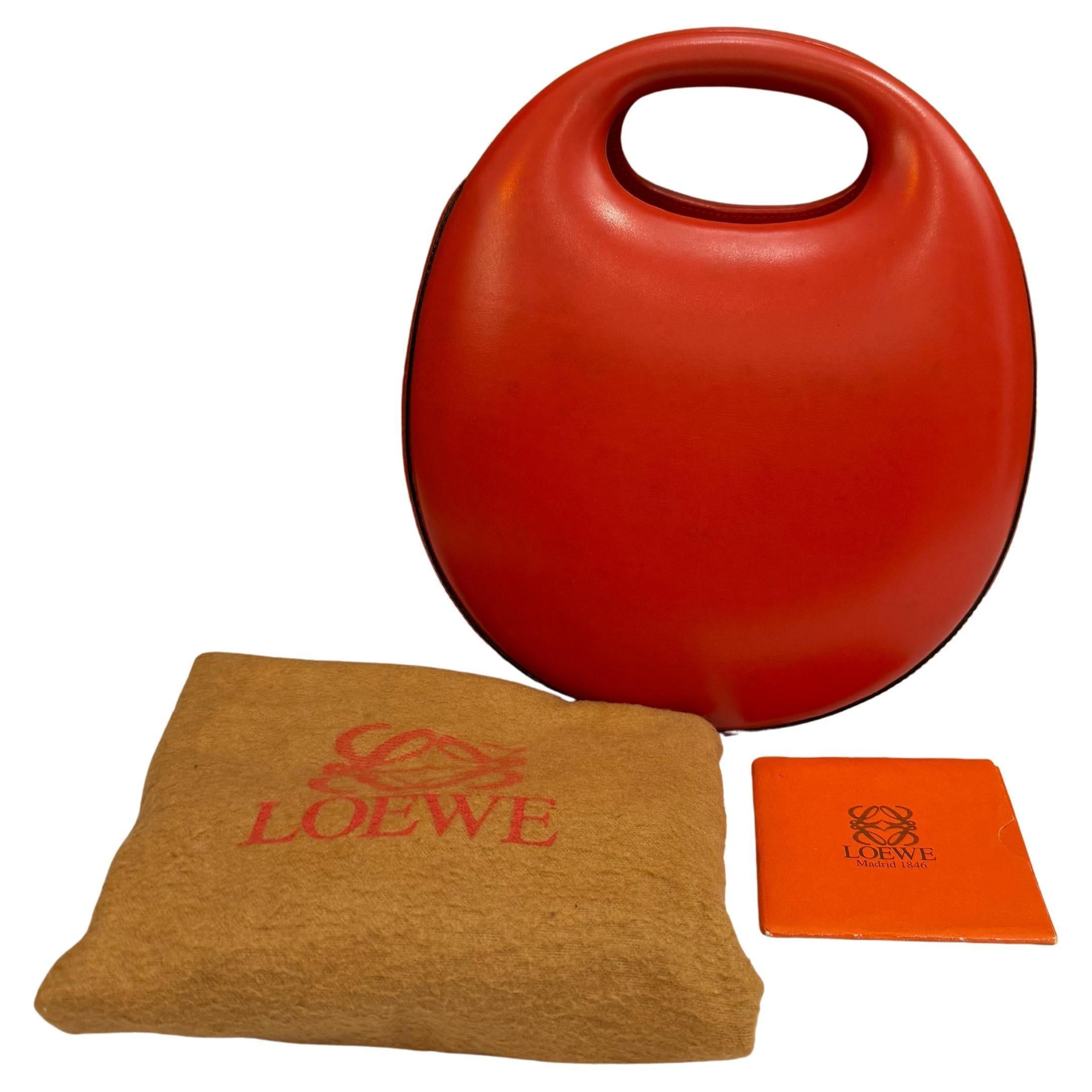 This vintage LOEWE egg bag is crafted of calfskin leather in red. Top magnetic snap closure opens to a beige leather interior featuring a zippered and a slip pocket. Made in spain. Measures approximately 8 x 9 x 4 inches. Comes with dust