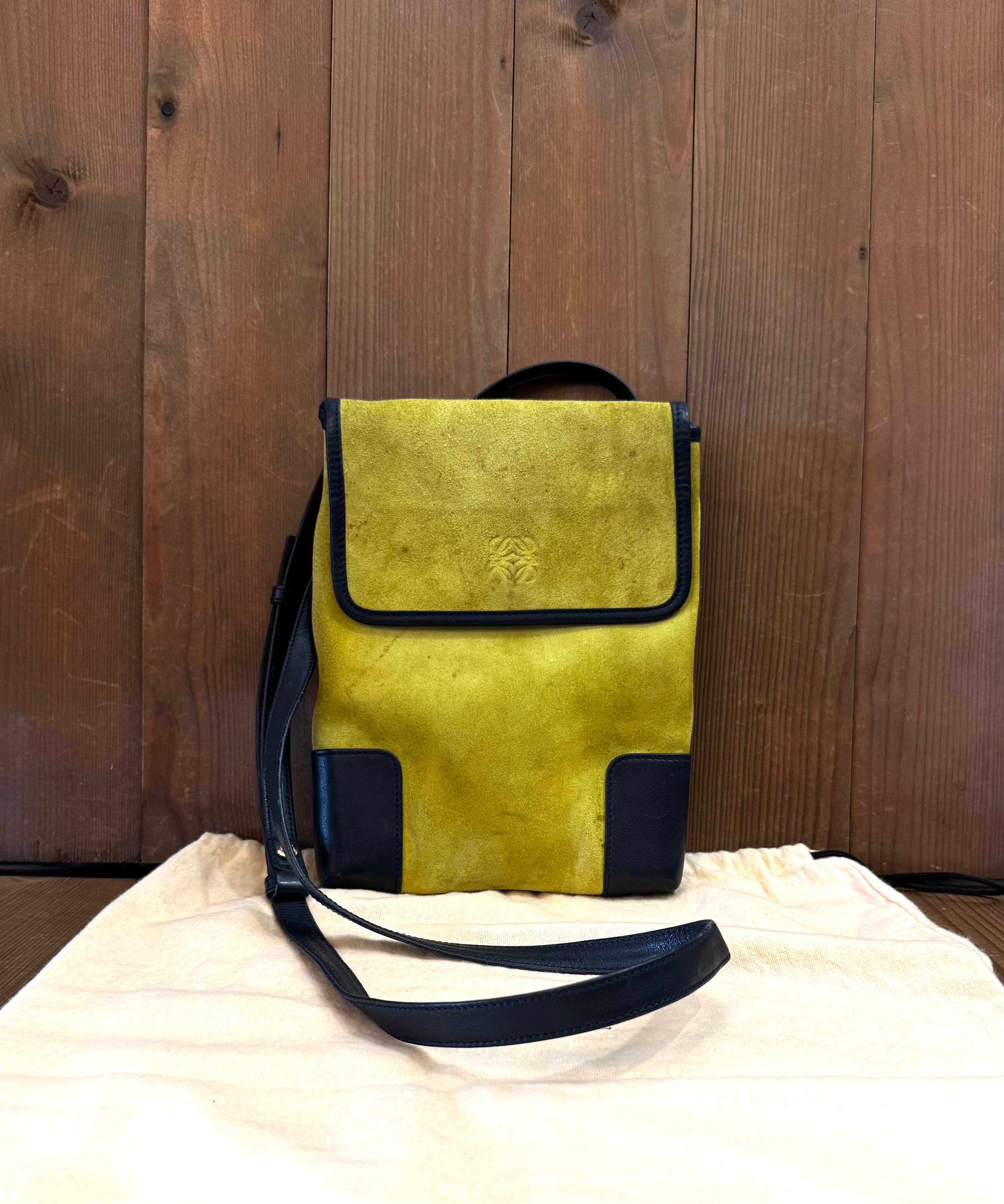Este bolso bandolera vintage LOEWE Anagram está confeccionado en ante de piel de ternero en amarillo mostaza, ribeteado en piel de ternero marrón y con un bolsillo trasero. La solapa frontal con cierre magnético a presión se abre a un interior sin