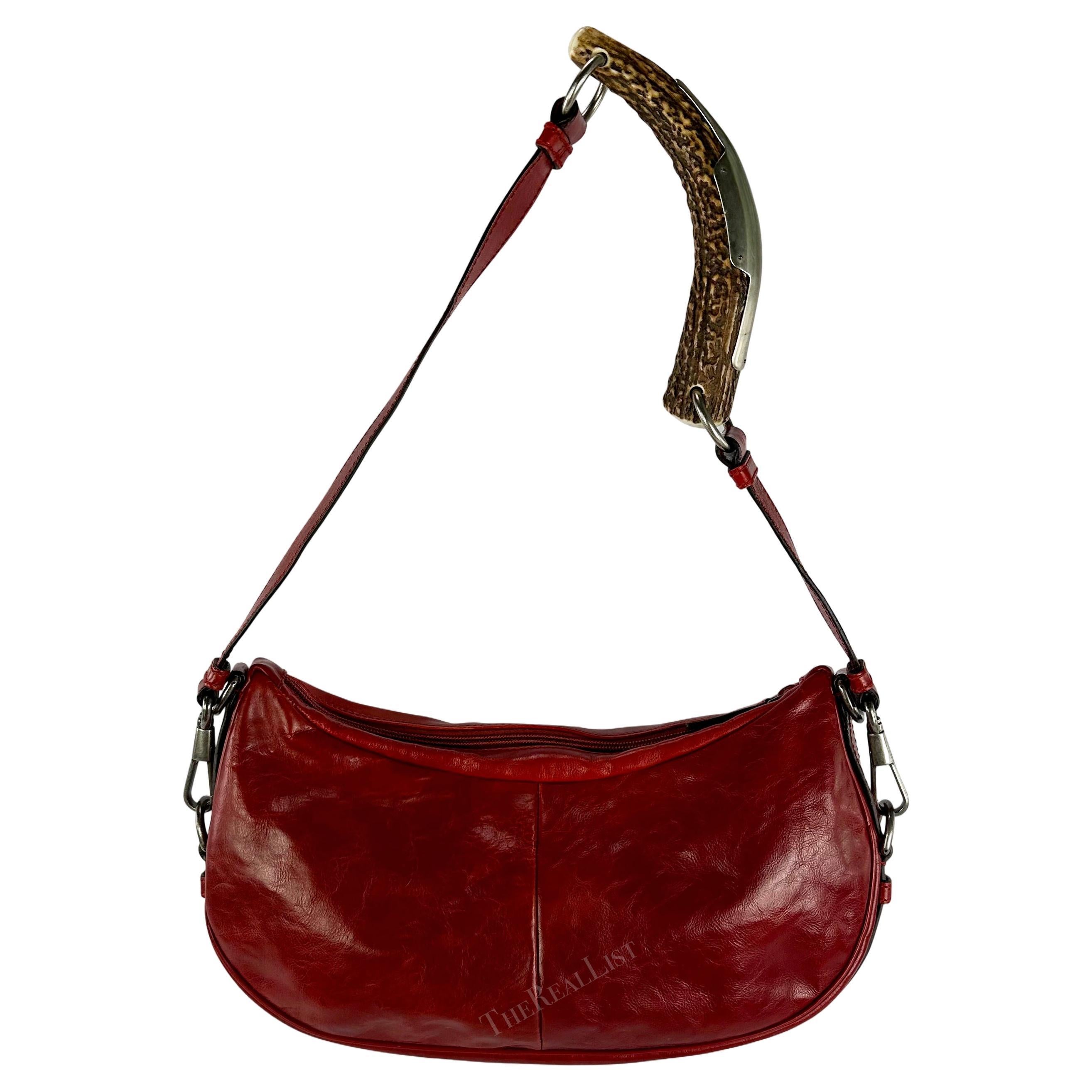 Datant du début des années 2000, ce remarquable sac à bandoulière en cuir rouge Yves Saint Laurent Rive Gauche style Mombassa a été conçu par Tom Ford. Entièrement fabriqué en cuir rouge légèrement usé, il est doté d'une poignée en corne accentuée