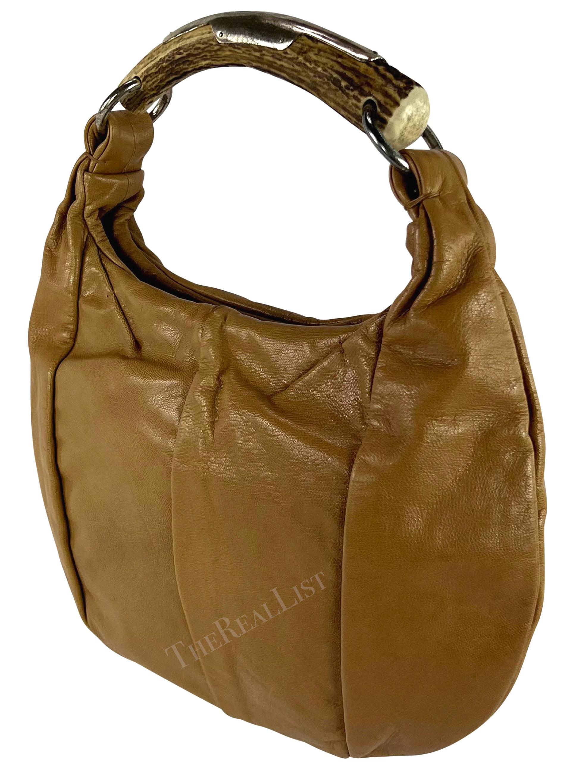 A chic light brown leather Yves Saint Laurent Mombassa bag from the early 2000s, designed by Tom Ford. Crafted from shiny tan aniline leather, this small shoulder bag features a round shape and is made complete with a metal accented horn handle.