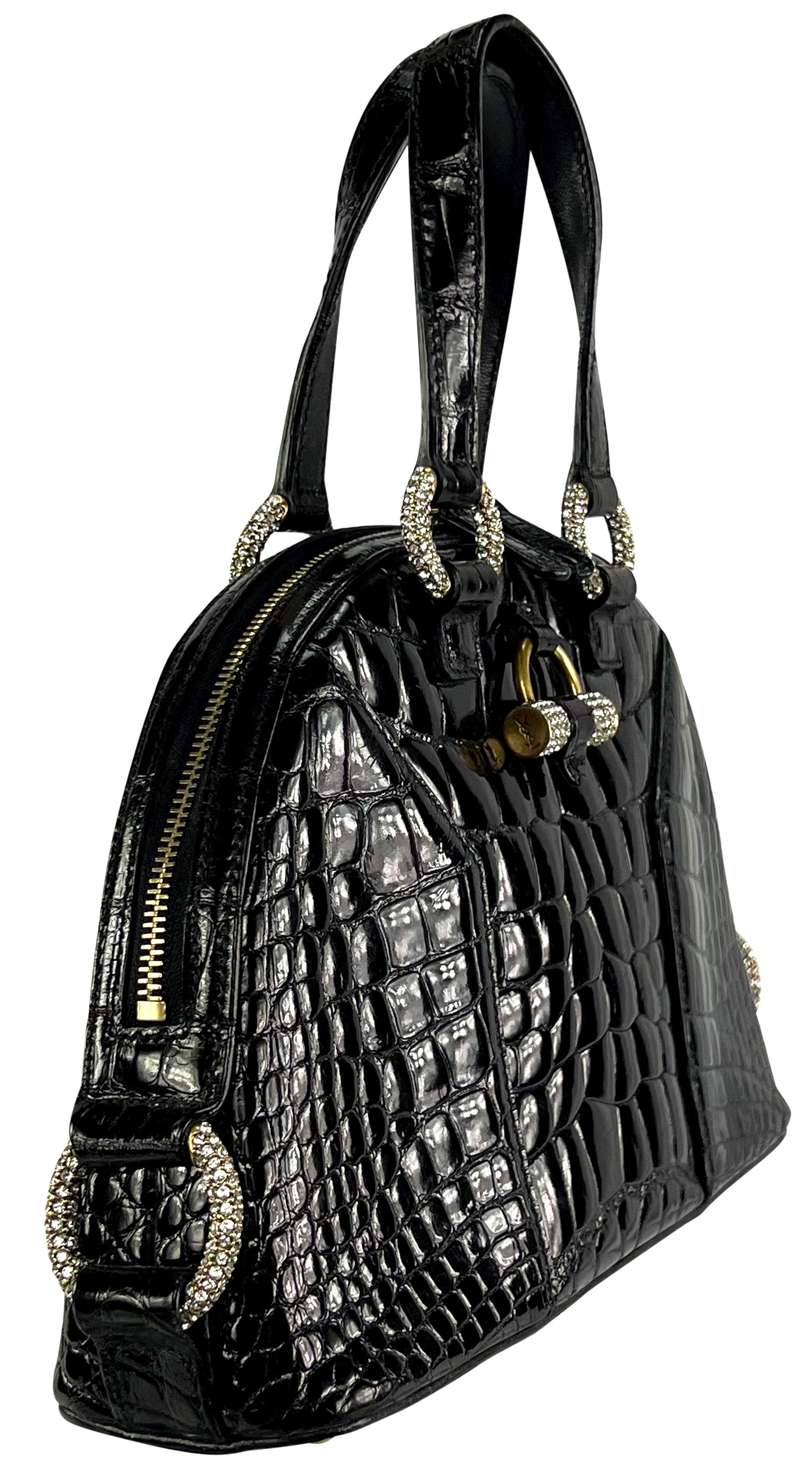 From the 2000s, this gorgeous, shiny black Yves Saint Laurent 'Muse' bag is constructed entirely of glossy crocodile. Designed by Stefano Pilati, this petite bag features a dome shape and is complete with gold-tone rhinestone-covered hardware. The