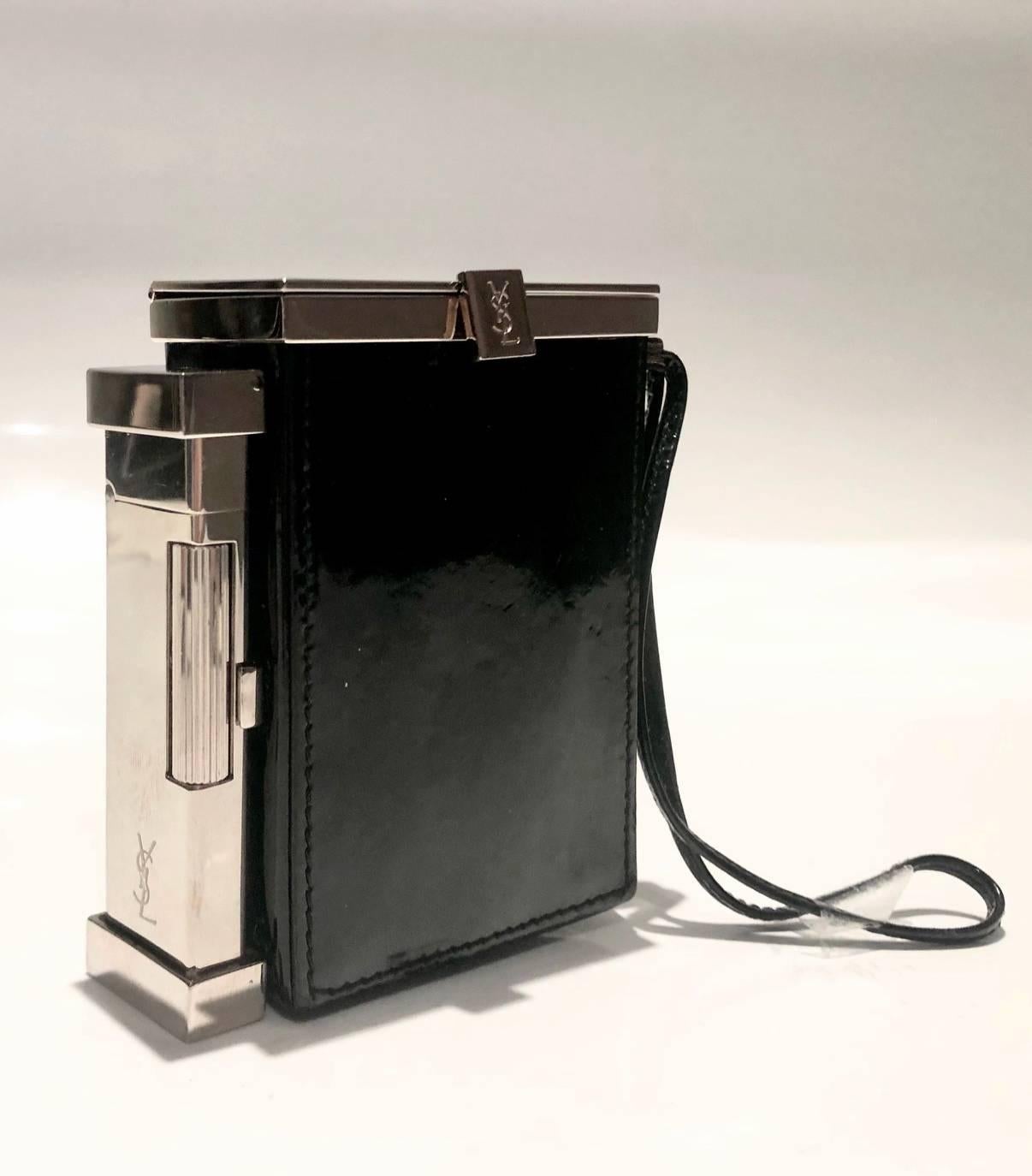 YVES SAINT LAURENT SMOKING BOX WITH LIGHTER
Amazing vintage smoking box and purse from Yves Saint Laurent designed by Tom Ford in the late 90s/early 00s. Silver tone metal ware, black patent leather, clutch closure with logo details, silver tine