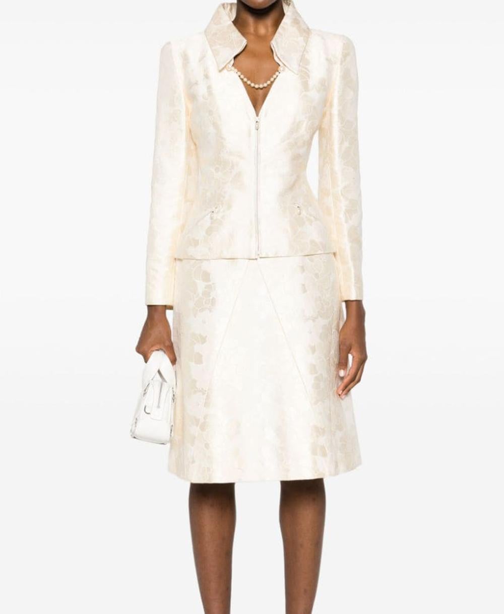 Chanel light ivory camellia pattern two-piece skirt suit featuring a cotton-silk blend fabric, a signature Camélia motive, faux-pearl embellishment.
For the jacket featuring a classic collar, a V-neck, a front two-way zip fastening, long sleeves,