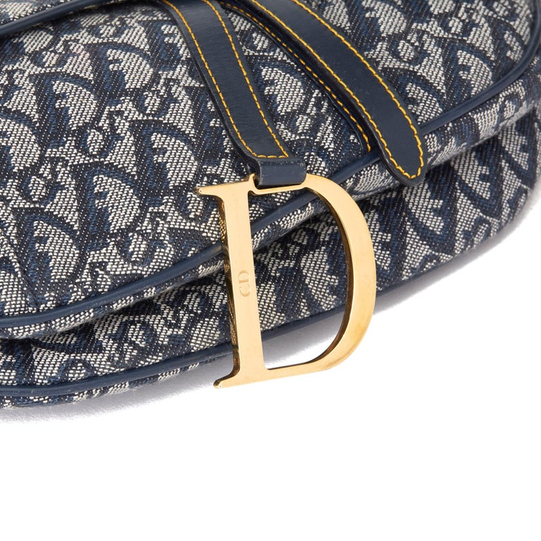 Sold at Auction: Christian Dior - a saddle pochette in blue Diorissimo  canvas, circa 2001, blue leather trims and pipings with contrasting yellow  stitching, zip closure and fabric-lined interior, gold-tone hardware. Date