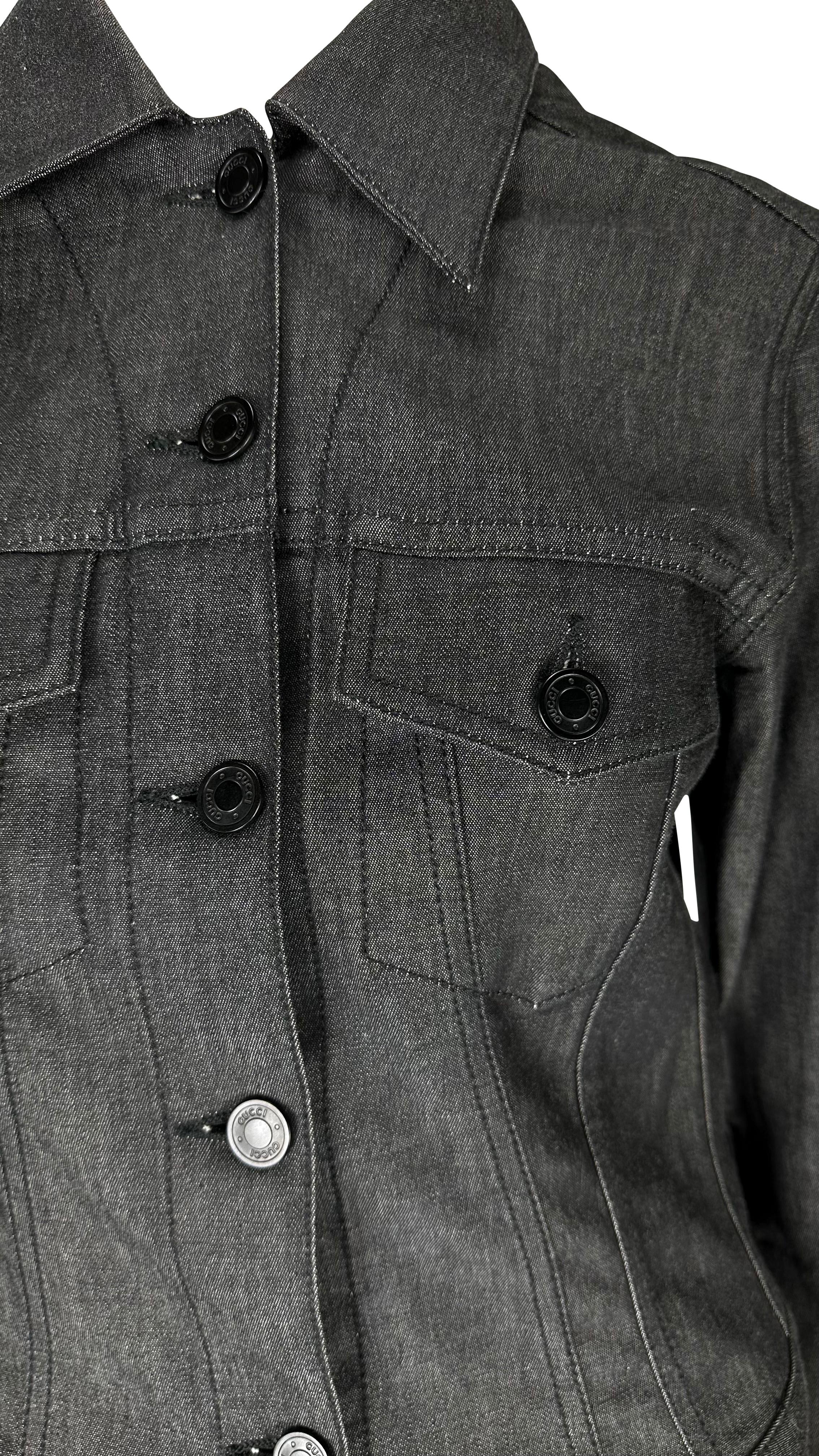 Wir präsentieren eine schwarze Jeansjacke im Trucker-Stil von Gucci, entworfen von Tom Ford. Diese Jacke, die 2001 auf den Markt kam, verleiht der durchschnittlichen Jeansjacke den perfekten Luxus-Pop. Die Vorderseite der Jacke ist mit schwarzen