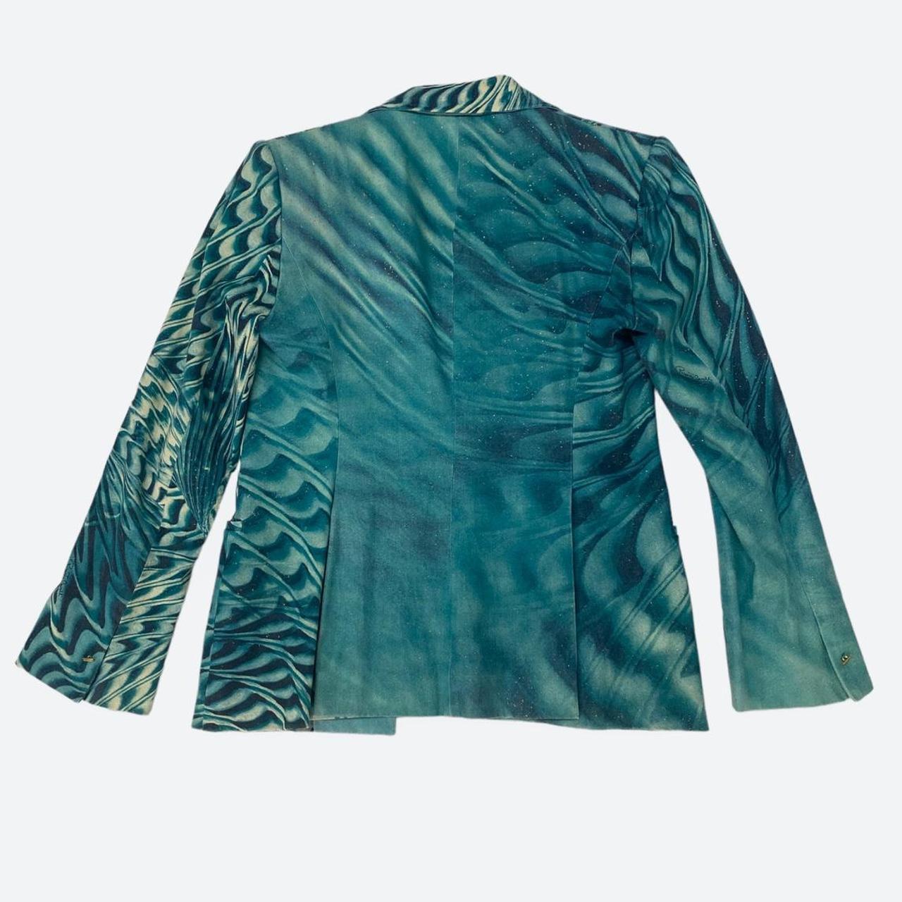 The teal blue swirling print of this blazer twists and centres in the left side of the jacket’s chest, creating a stunning dynamic illusion to a classic, formal type of garment. The jacket is also adorned with small gold specks printed all over the