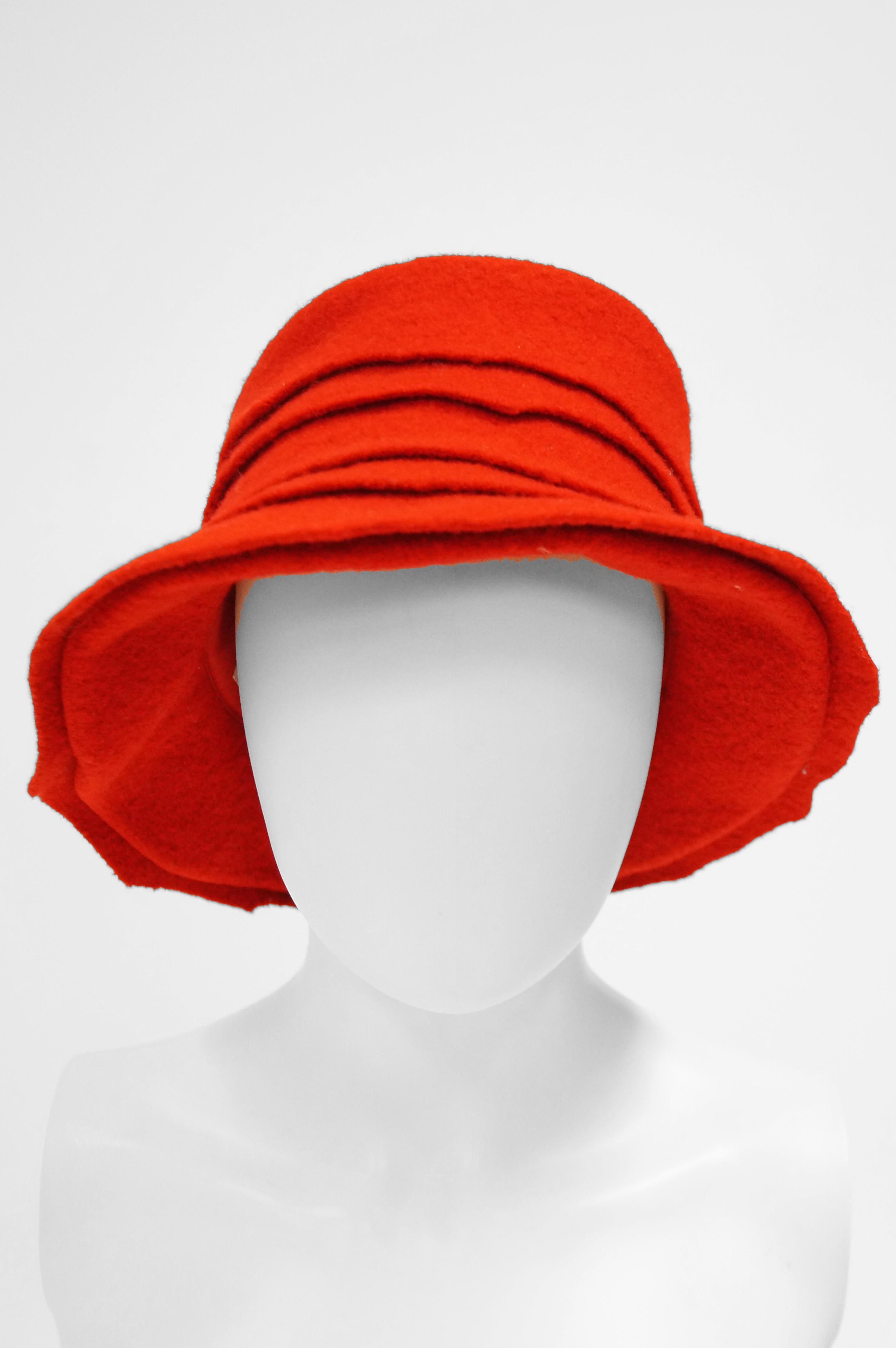 Striking! Fun bright red hat by Stephen Jones! This brilliant bucket hat features a high, round crown with a wide, sloping brim giving the piece a cloche - like look. The hat is composed of five stacked layers of felt with playful asymmetric edges,