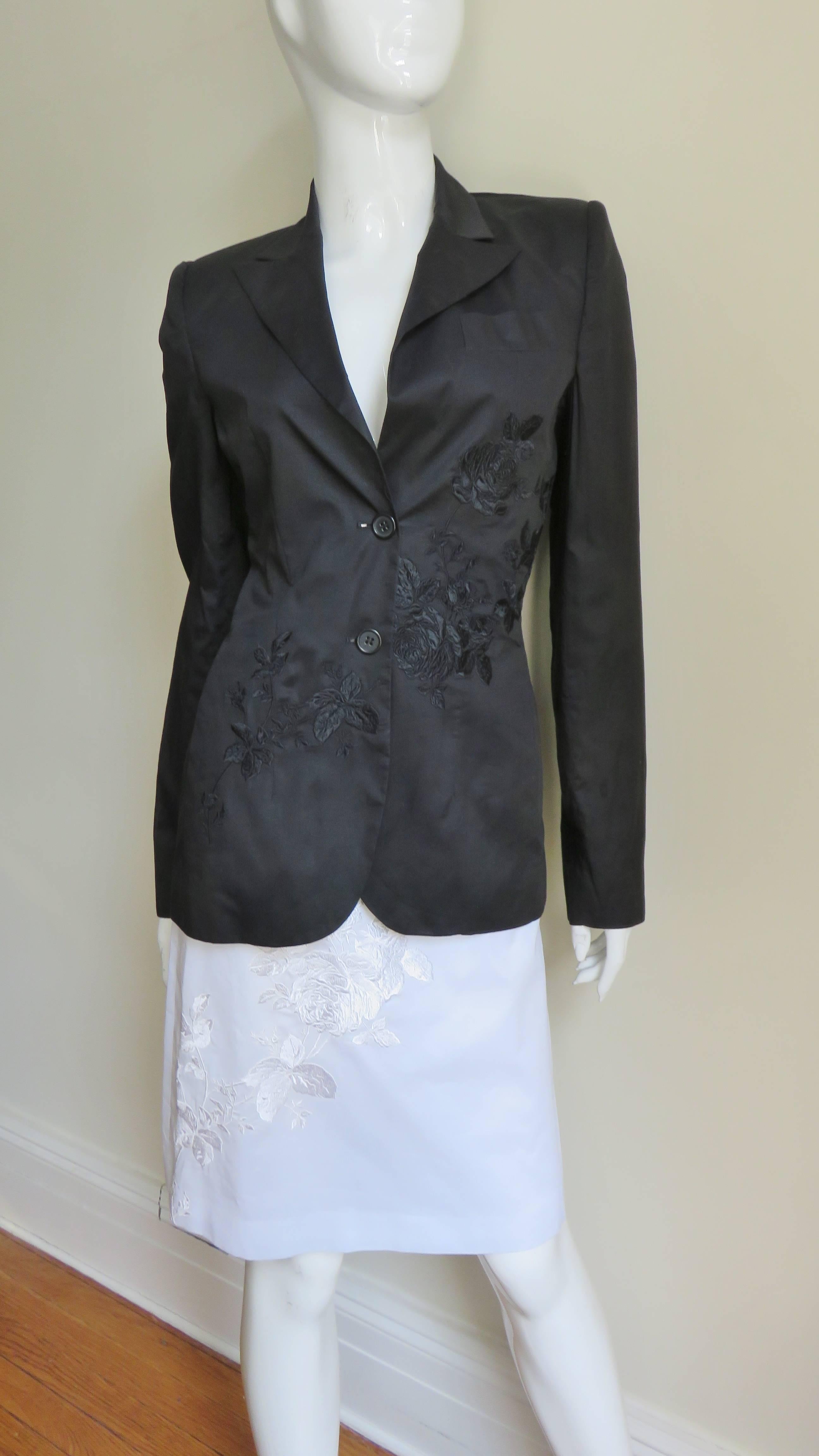 A fabulous silk/linen black skirt suit from Alexander McQueen including an additional matching white skirt.  The jacket has peak lapels, a breast pocket, small shoulder padding, side seam pockets and 2 button front closure. It has intricate flower