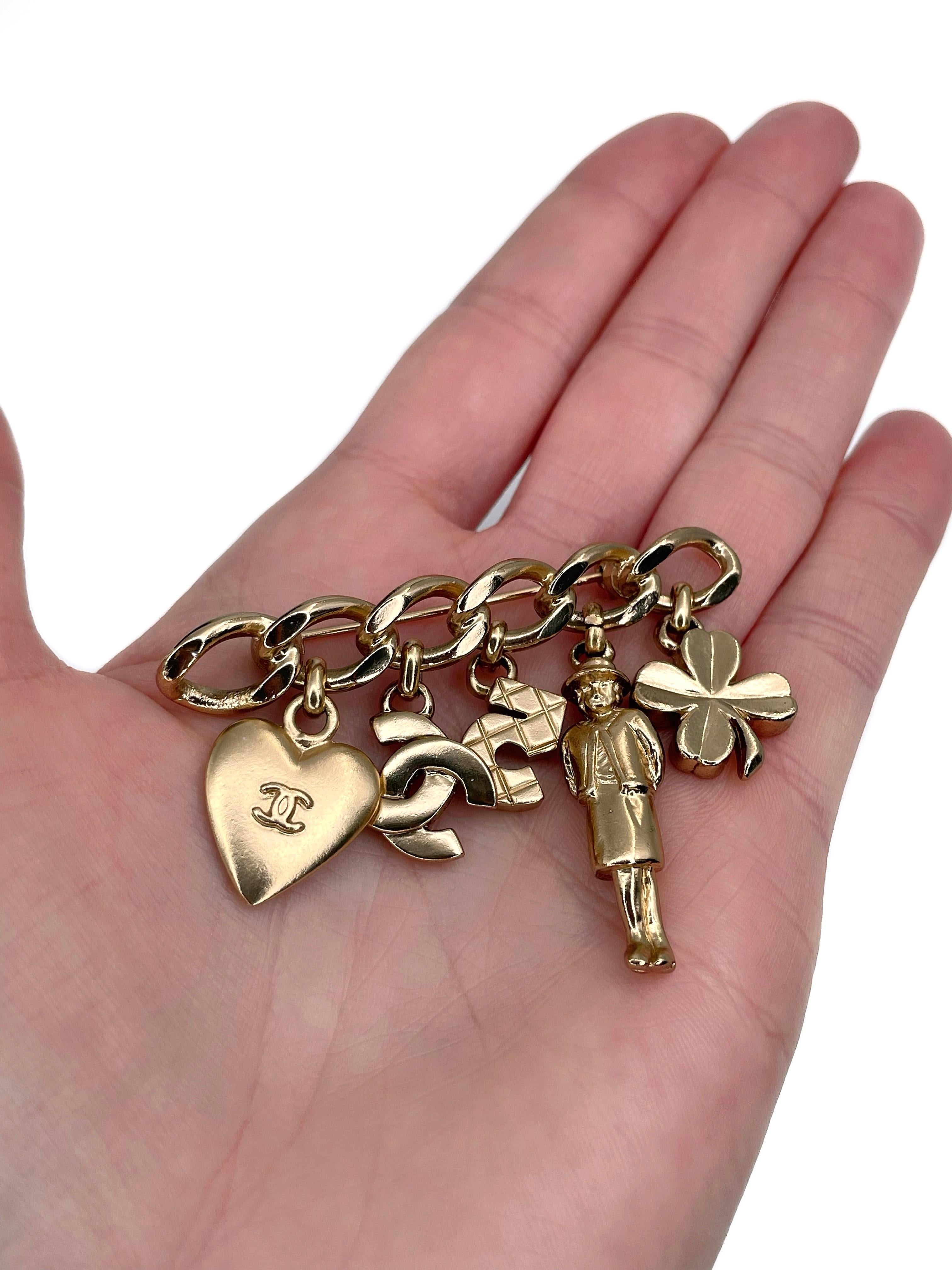 This is a charm bar brooch designed by Chanel for 2002 collection. The piece is gold plated. It features heart, CC logo, number five, madame Coco, clover charms. 

Signed: ©Chanel® 02P. Made in France

Bar length: 6cm
Width (at max): 4.5cm

———

If
