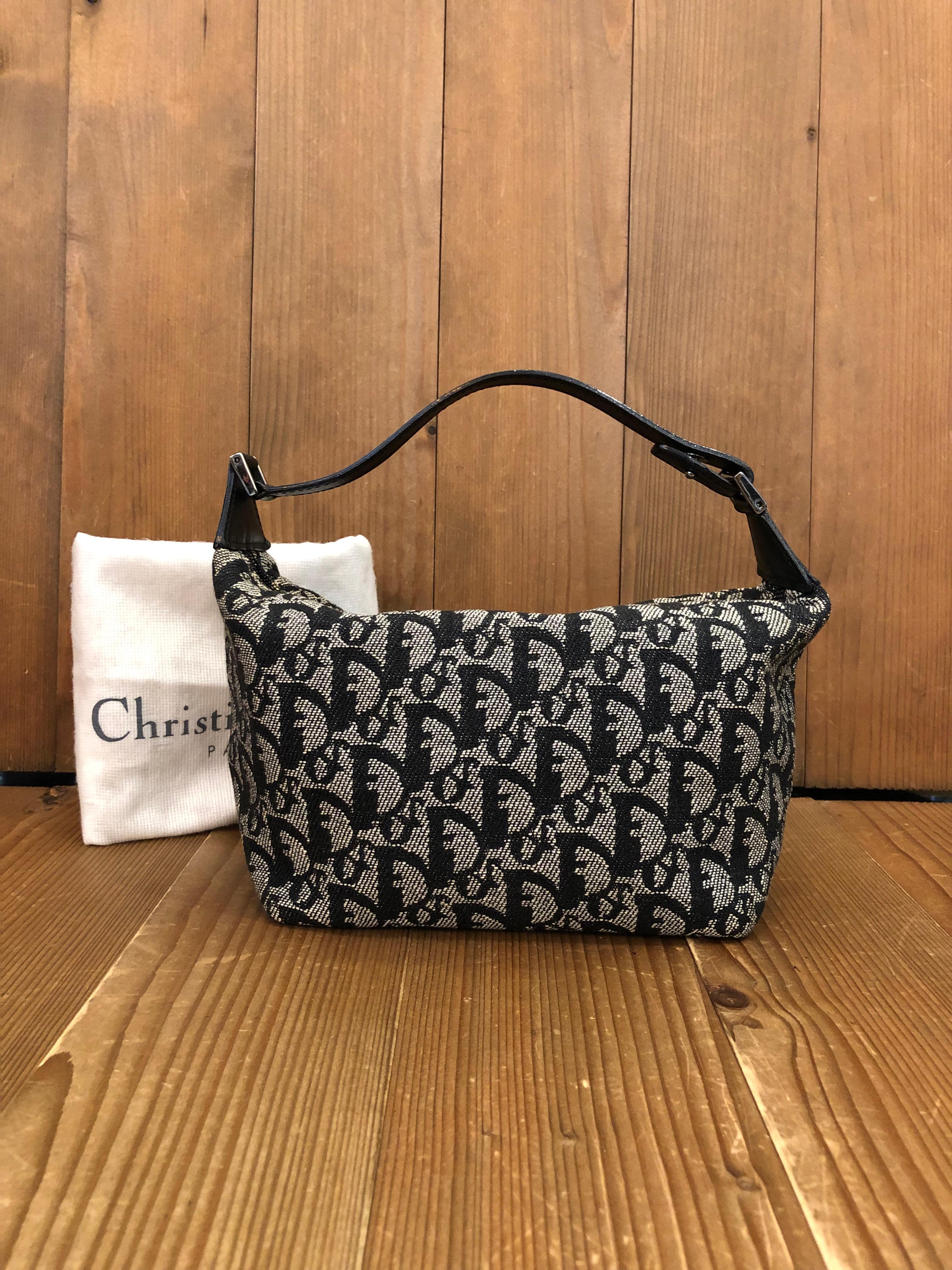 This vintage Christian Dior pouch handbag is crafted of Dior’s iconic trotter jacquard in black trimmed with black leather. Zip top closure opens to a black fabric interior with one zippered pocket. Made in Spain. Compact in size yet big enough for