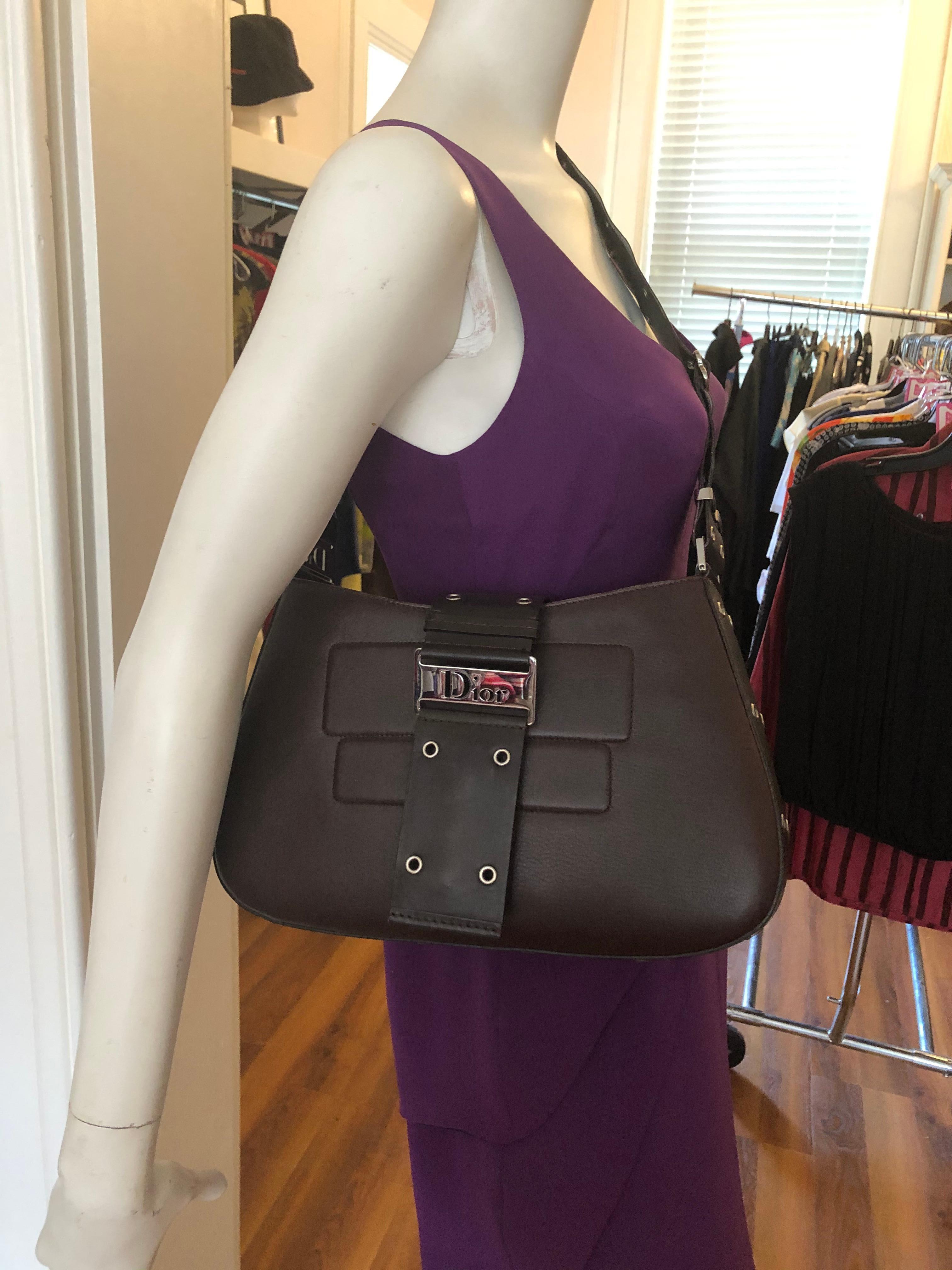 In very good condition this April 2002 (MA-0042) leather bag designed by John Galliano. It can be worn as a crossbody (see pictures), as well as a shoulder bag. It has a flap pocket; grommet accents; silver hardware; an outside back slit pocket, and