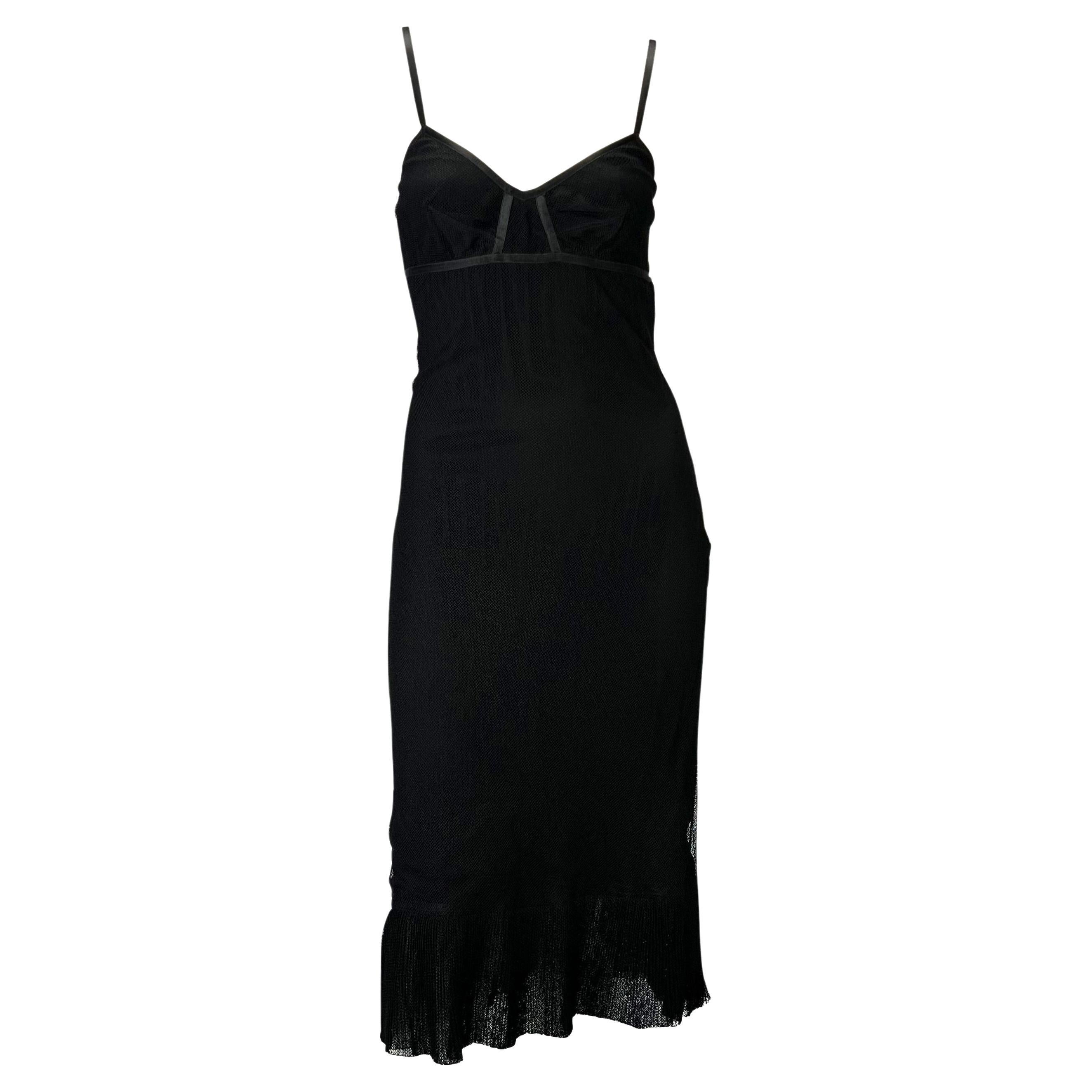 Presenting a head-turning little black dress designed by Tom Ford for Gucci in 2002. A tulle/mesh covers a built-in bra connected to a flared skirt with a pleated hem and lace-up corset detailing. Below a partially exposed back, this LBD can be