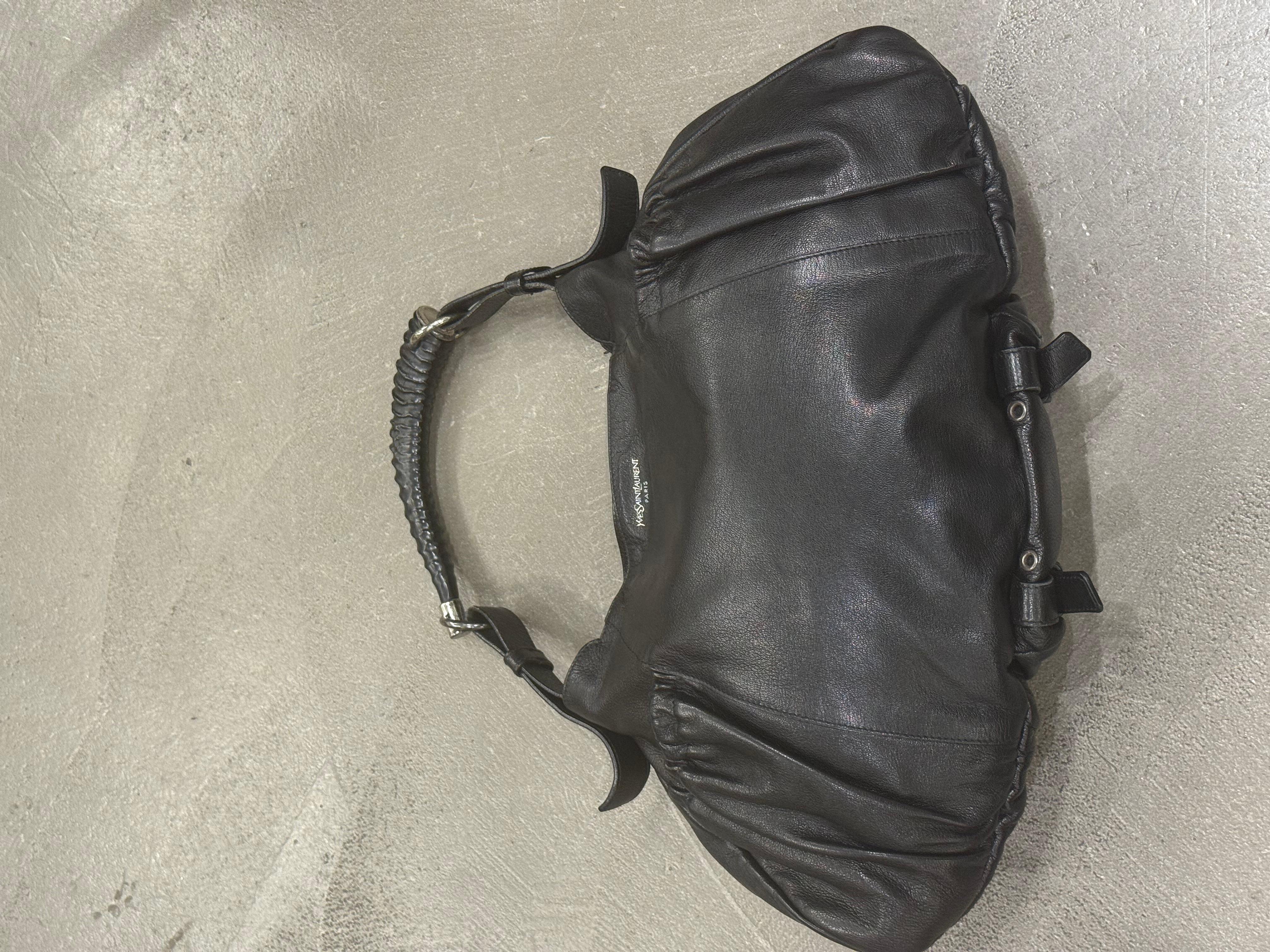 2002 Saint Laurent Mombasa Mala bag

This early-2000s Saint Laurent Mombasa Mala bag captures the raw, tactile elegance that defined the era under Tom Ford. Crafted from supple black leather, it features the signature sculptural Mombasa handle with