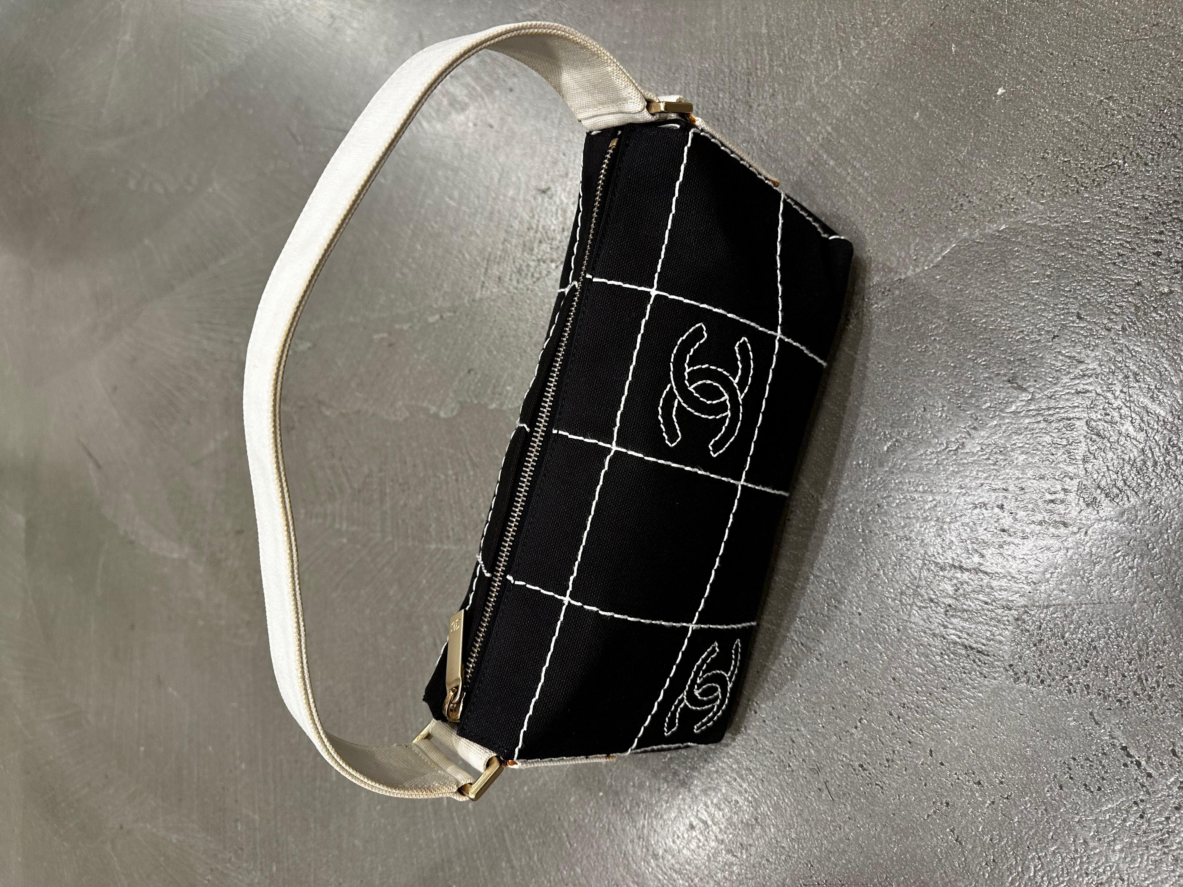 Ce sac à bandoulière Chanel de 2003-2004 est une pièce raffinée qui allie l'élégance du début des années 2000 aux détails intemporels de la signature. Fabrice en tissu noir, le sac est orné d'un motif de points de grille blanc distinctif qui ajoute