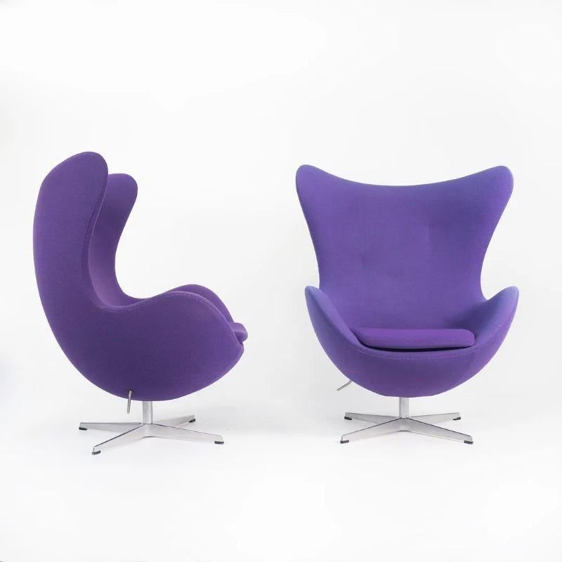 This is a single Egg Chair designed by Arne Jacobsen and produced by Fritz Hansen of Denmark in 2003. The price listed is for one chair, though two are available. Each chair is upholstered in a purple hopsack-like upholstery, likely Tonus by