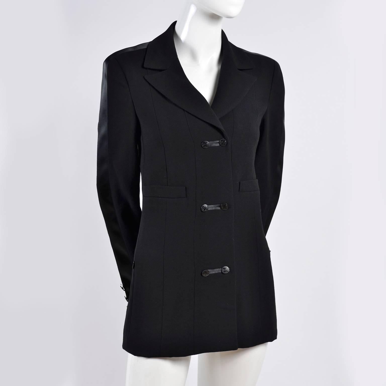 This is a beautiful Chanel Autumn 2003 black wool blazer with double breasted cc Logo buttons up the front, decorative pockets and functional slit zip front pockets. There is a wide satin stripe of fabric on each sleeve that runs up the shoulders to